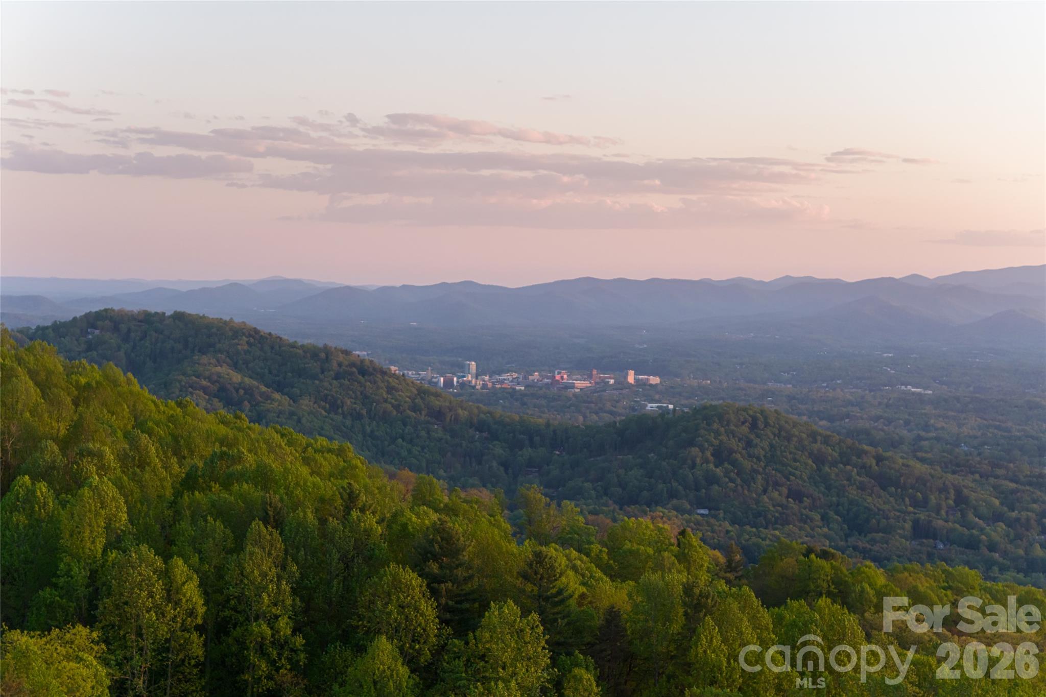 A rare opportunity to acquire a true legacy property defined by privacy, scale, and massive, long-range views of the Blue Ridge Mountains. Set along iconic Elk Mountain Scenic Highway at over 3,000 feet in elevation, this one-of-a-kind offering encompasses a vast, wooded landscape ideally suited for a private residential estate, generational compound, development, or select commercial endeavors. Natural ridgelines, soft knolls, mature hardwoods, and tranquil streams weave throughout the land, creating an immersive and secluded setting while remaining minutes from downtown Asheville’s celebrated dining, arts, and healthcare, as well as the Country Club of Asheville and the Blue Ridge Parkway. The topography lends itself to architecturally significant residences designed to capture sweeping mountain vistas and maximize privacy, with opportunities for private trails, outdoor living, and potential conservation easement benefits. In addition to the full parcel offered in this listing, the property is also available as two separately listed, smaller acreage tracts, providing flexibility for purchasers who may prefer to acquire a more tailored portion of the land. With its combination of expansive acreage, commanding mountain views, flowing streams, and exceptional proximity to Asheville’s most desirable amenities, this offering stands apart as a rare and enduring investment in Western North Carolina.