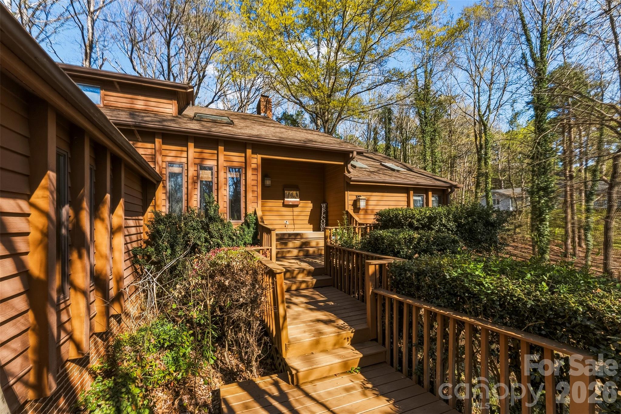 Welcome to your treehouse in the woods — inside one of the Lake Wylie's most remarkable communities.
Tucked toward the back of the prestigious, gated River Hills neighborhood on a quiet cul-de-sac, this 3-bedroom, 2.5-bath contemporary home sits on nearly half an acre surrounded by mature hardwoods, azaleas, and dogwood trees. It's private, peaceful, and completely one-of-a-kind.

The main level is designed for both everyday living and entertaining. Hardwood floors run through the foyer, kitchen, dining room, and living room. The great room features a stunning stone wood-burning fireplace and soaring ceilings. The kitchen offers a center island, solid surface countertops, and a breakfast area bathed in natural light from the adjacent sunroom — a standout space perfect for a home office, reading room, or morning retreat. The master suite is on the main level with a large walk-in closet and ensuite with new flooring. Main level laundry completes the thoughtful layout.

Upstairs, two generously sized bedrooms share a full bath with double sinks, plus a large loft ideal for a second office, playroom, or media space — and a flex room perfect for a craft room, studio, or 4th sleeping area.
Step outside to the expansive rear deck and hot tub deck — made for entertaining, and stunning in the spring when the azaleas bloom.  No lawnmower needed on this home, it's nested in it's natural surrounds.

Enjoy the outdoors with large backyard deck accessible from the living room, or sunroom.  On the back deck you'll also find a 40 jet hot tub (hardly used).  

The large unfinished basement offers serious storage and workshop potential. River Hills amenities are unmatched: gated entry, golf course, tennis and pickleball courts, fitness center, horse riding, community garden, walking trails, and direct access to Lake Wylie with a private beach. Camp Thunderbird is steps away. This home is within walking distance to South Point Beach & Park. You won't find a better location within the community.

A rare find for buyers seeking space, privacy, lifestyle, and a home that truly stands apart.