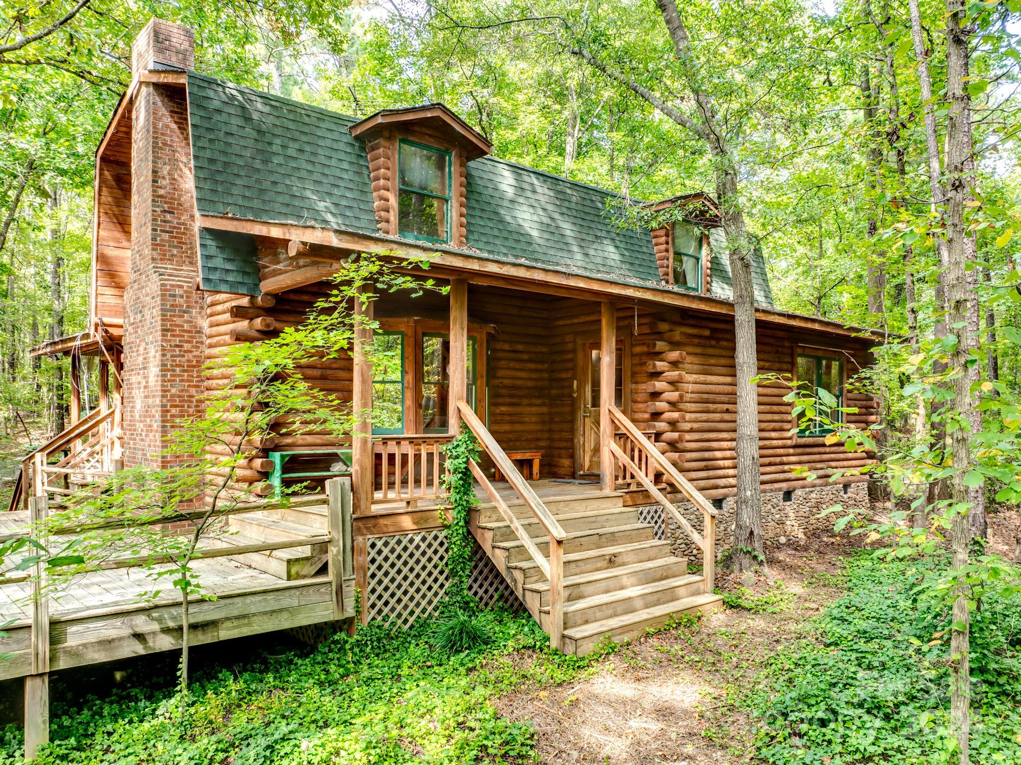 Welcome home! Tucked away on over 50 acres of secluded, private land, this log cabin offers the ultimate getaway. With 4 bedrooms and 3 full baths, this home is ideal for those seeking both comfort & privacy.  The great room features impressive vaulted ceilings, a charming stone fireplace, & a large bay window seat that fills the space with natural light. The kitchen is ideal for entertaining, featuring a spacious island, dual ovens, & a cozy breakfast nook with scenic views of nature. Two versatile flex spaces can be tailored to fit your needs—perfect for a home office or craft room. Skylights in the upstairs bedroom & flex room bring in the sunshine, creating a warm and welcoming ambiance throughout the home. Step outside onto the welcoming front porch or unwind on the spacious deck, soaking in the peaceful surroundings. This secluded property offers a true retreat, with two creeks flowing through the landscape, providing unmatched privacy and nature's beauty right at your doorstep.