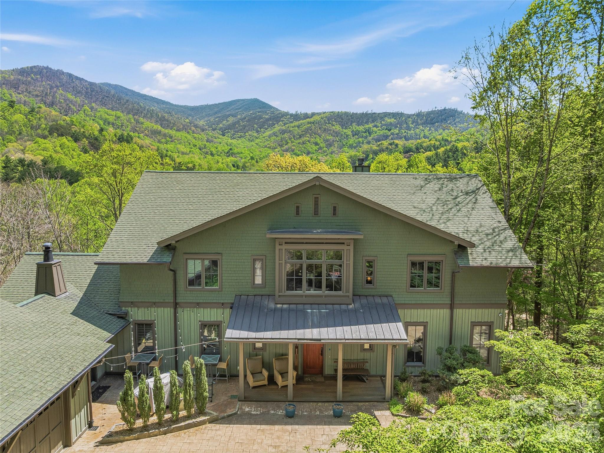 Set across 5.5 private acres in the coveted Oxbow Crossing community, just 20 minutes from Downtown Asheville, 39 Oxbow Crossing is a striking contemporary estate where architecture, craftsmanship, and the Blue Ridge landscape converge. Encompassing over 6,000 square feet of thoughtfully designed living, the residence offers a rare opportunity for buyers seeking a home that is both architecturally distinctive and deeply connected to its mountain setting.

Dramatic soaring ceilings and walls of glass frame expansive mountain vistas, filling the home with natural light and creating a seamless dialogue between interior spaces and the surrounding landscape. Custom metalwork, refined materials, and clean architectural lines give the home a sophisticated design language that feels both modern and timeless.

At the heart of the home, the chef’s kitchen is a true culinary showpiece, designed for both daily living and memorable entertaining. Premium appliances include Gaggenau double ovens and gas range, Sub-Zero refrigeration, an EarthStone wood-fired pizza oven, and a built-in Miele coffee station, complemented by custom cabinetry, soapstone and stainless steel countertops, and an exceptionally generous walk-in pantry. The kitchen flows effortlessly into the living and dining areas, where a covered terrace invites gatherings against a backdrop of layered mountain views.

The main level also offers remarkable flexibility, with a large en-suite bedroom and adjacent office that can easily be combined to create a luxurious main-level primary suite. The home was also designed with elevator-ready framing, allowing for future accessibility and multigenerational living.

Upstairs, an open gallery hallway overlooks the dramatic great room and frames sweeping views beyond. The primary suite is a private retreat, featuring a spa-inspired bath with soaking tub, walk-in shower, double vanities, and a custom closet. Two additional spacious en-suite bedrooms, a sitting room or studio, and a full laundry room complete the upper level.

The daylight lower level expands the home’s lifestyle offerings with a second living area, guest suite, billiards and game room, custom bar, fitness space, and an oversized workshop—ideal for collectors, craftsmen, or hobbyists.

Modern systems ensure comfort and performance, including gigabit Ethernet, three-zone HVAC, dual tankless water heaters, propane heat, a whole-house generator, and an EV-ready two-car garage.

Positioned minutes from Downtown Weaverville, Asheville’s acclaimed culinary and arts scene, and the Blue Ridge Parkway, this exceptional estate delivers privacy, architectural integrity, and a lifestyle defined by mountain beauty and modern design.
