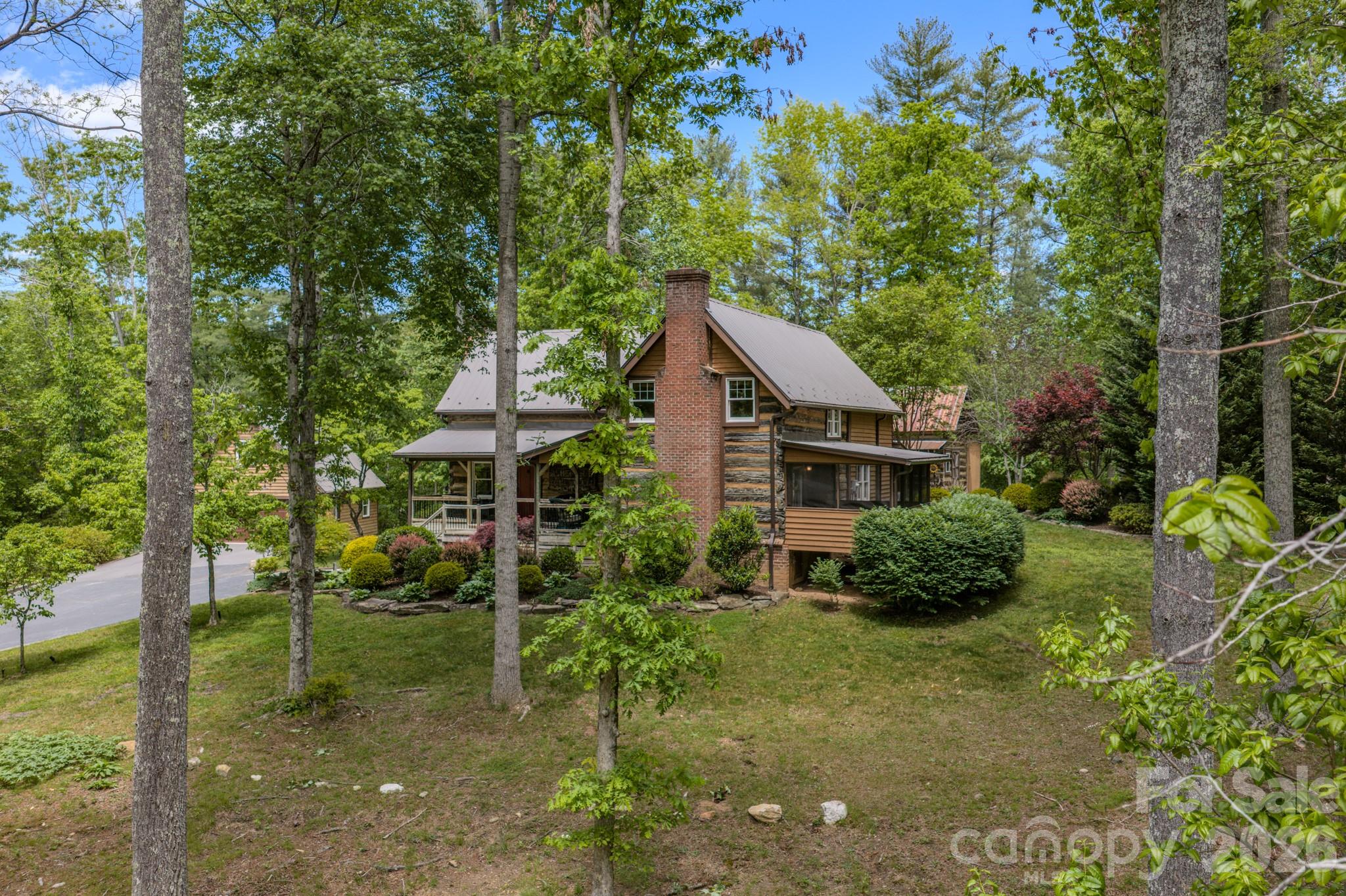Surrounded by the natural beauty of Western North Carolina, this peaceful and private setting offers both tranquility and convenience, just a short drive to Asheville. Step into a rare blend of history and craftsmanship with this one-of-kind property nestled on the original location of the first school in the Fairview, NC - Possum Trot School  Built by dismantling 5 original log cabins located in Madison County and Leicester and relocating them to Fairview where they were reassembled, by the owner,  into the present configuration.  This home showcases authentic materials dating back to the 1860's.  The original doors and other features offer timeless character that combines rustic charm with comfortable living.  The home has been modernized while maintaining the log cabin feel/look on the exterior and interior. The property also features a detached double garage with ample storage space above - perfect for a workshop, studio, or additional storage needs.  Adding even more versatility, a separate smaller cabin with electricity provides the ideal space for a writer's retreat, guest accommodations, or private office.  With its layout and setting, the property presents an excellent opportunity to create a family homestead, wedding venue or many other commercial uses.
