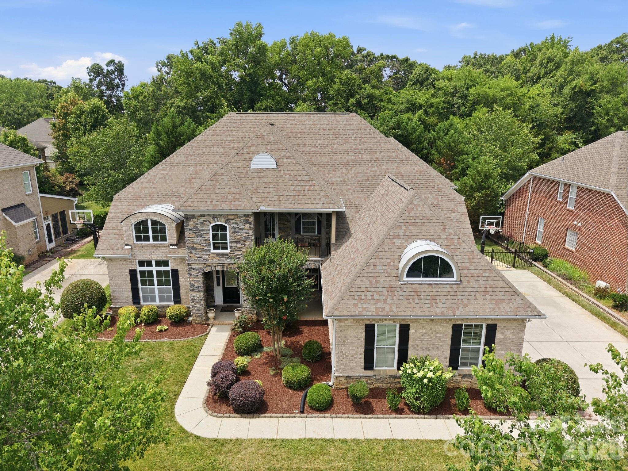 Stunning all-brick home featuring a desirable 3-car side-load garage, nestled on a beautifully landscaped, fenced homesite backing to a private natural area. Thoughtfully designed with neutral décor throughout, this move-in-ready home offers an exceptional blend of elegance, comfort, functionality, and privacy.

The spacious main-level primary suite provides a private retreat, while the thoughtfully designed floor plan includes a formal dining room, family room, living room, and two dedicated office spaces—perfect for today's flexible lifestyle. The gourmet kitchen showcases freshly painted white cabinetry, granite countertops, double wall ovens, and ample space for entertaining and everyday living.

Designed for convenience, the home features dual staircases, a generous loft ideal for family gatherings, and four additional bedrooms upstairs. Two bedrooms offer private en-suite baths, while the remaining two share a Jack-and-Jill bathroom, creating an ideal layout for families of all sizes.

Step outside to enjoy the expansive covered porch complete with an outdoor kitchen and built-in grill, overlooking a serene, private backyard surrounded by mature landscaping and natural views—an ideal setting for relaxation and entertaining.

Recent updates include fresh interior paint, new carpeting, freshly painted cabinetry with updated hardware and a recently installed Tesla Wall Charger, providing convenient at-home EV charging.

Ideally situated in one of Ballantyne's most sought-after locations, this home is within walking distance of Rea Farms and just minutes from Waverly, placing premier shopping, dining, fitness, and entertainment at your fingertips. With convenient access to I-485 and top-rated schools, this exceptional property offers a rare blend of privacy, convenience, and everyday luxury. Don't miss your opportunity to make it yours.