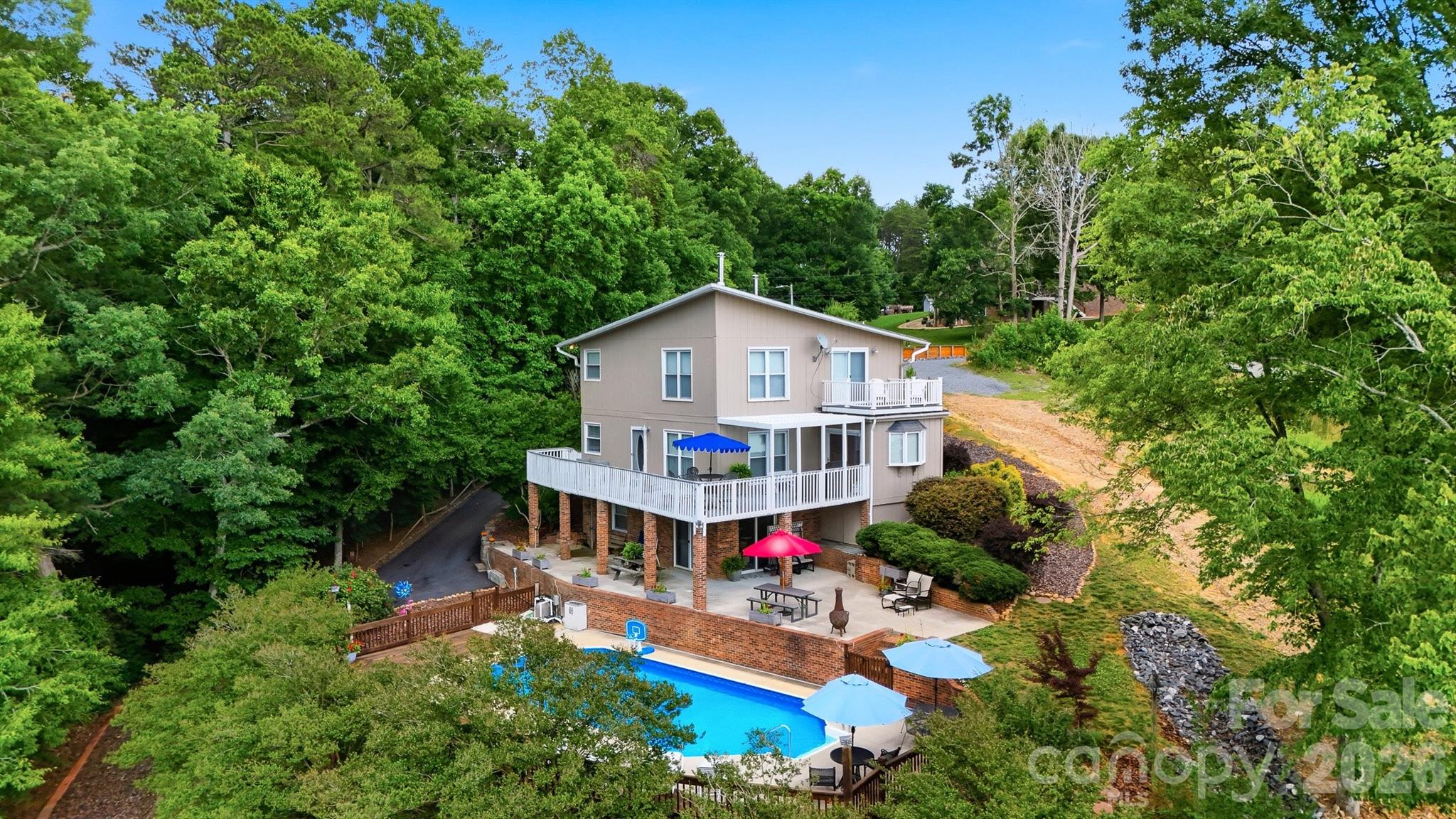 Feel like you’re on vacation year-round at this Lake Hickory waterfront retreat, perfectly positioned just off the main channel for exceptional lake access and beautiful water views. This uniquely designed home offers inviting indoor and outdoor living spaces, including wrap-around decking just off the main level, a sparkling swimming pool, a covered two-slip boat dock, an additional floating dock, and a beach area.

Inside, the main level features a dramatic two-story living room filled with natural light from ample windows showcasing lake views. Wooden ceiling beams add warmth and character to the kitchen and living room, while the eat-in kitchen offers even more natural light and a comfortable space to gather. A bedroom, office, and full bath on the main level provide convenience and flexibility.

Upstairs, you’ll find a spacious primary ensuite along with an additional ensuite bedroom, creating comfortable private spaces for family and guests. The lower level is designed for entertaining, featuring a recreational area with exposed brick walls, an additional bedroom, a full bathroom, plus laundry and utility space. Step outside to the patio spanning the lower level, complete with an outdoor shower and easy access to the pool.

A few short steps away, enjoy lake life at its finest from the covered two-slip fixed pier boat dock with two lifts, floating dock, and beach area. Recent updates and features include new HVAC in June 2026, roof replaced in 2015, septic pumped in May 2026, and county water. This Lake Hickory waterfront home offers the ideal blend of comfort, character, and year-round vacation living.