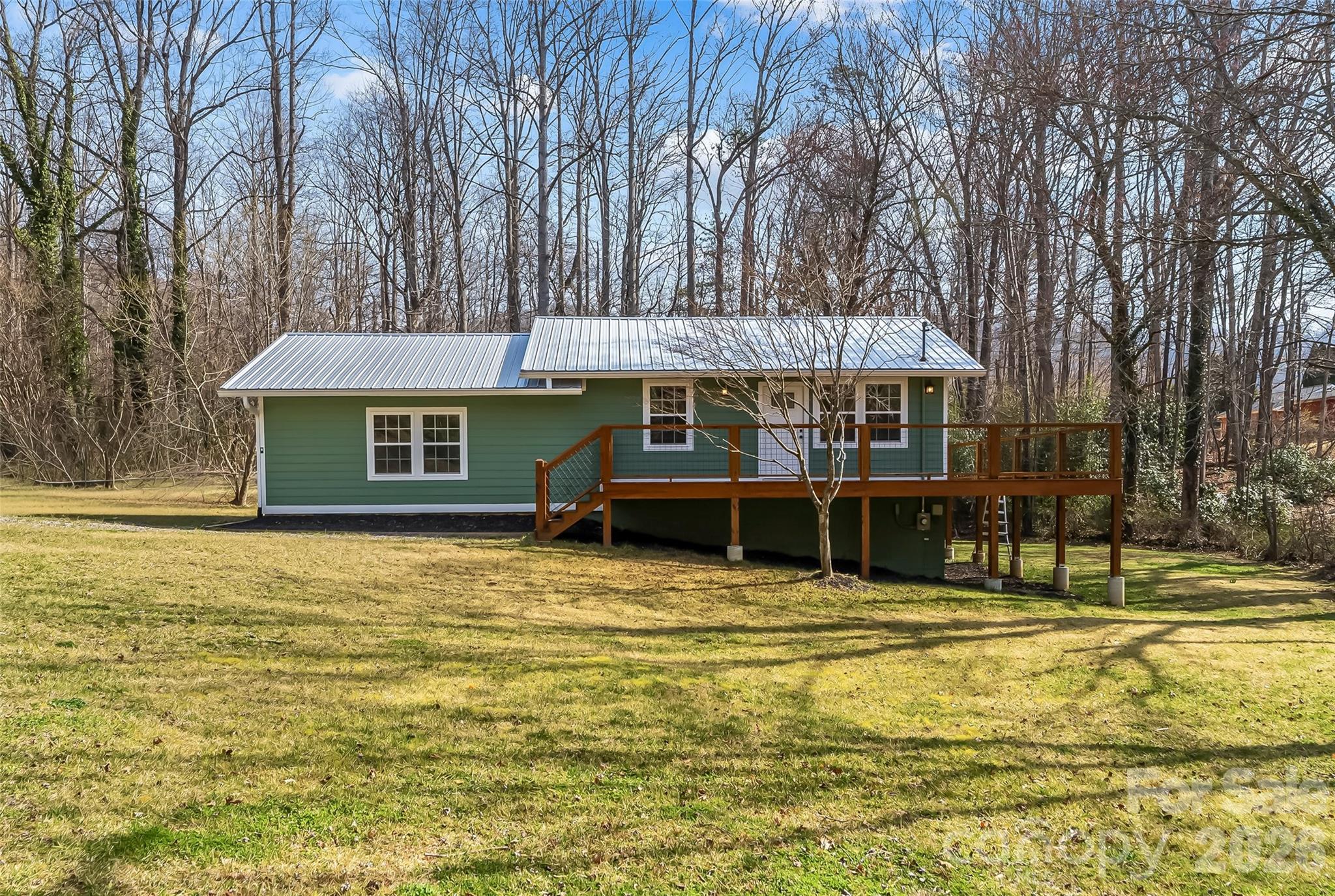Completely renovated from top to bottom! This move-in ready, one-level home with basement home, offers the rare combination of new finishes, thoughtful upgrades and a peaceful setting just minutes from town. Nearly every surface has been touched, creating the feel of a brand new home while preserving its original Black Mountain charm. Set on just under half an acre, the property features an expansive wraparound deck adding exceptional outdoor space for entertaining, gardening, relaxing, or enjoying your new surroundings. Inside, cathedral ceilings enhance the open living, kitchen, and dining area. The kitchen features top-of-the-line cabinetry, Dekton countertops, brand new Whirlpool appliances, and a spacious walk-in pantry. The primary bedroom includes a large walk in closet along with unique water closet for convenience. All closets throughout feature custom built-in organization systems, and most include dimmable lighting. The 3rd bedroom has a private exterior entrance offering versatility. The finished basement, with exterior entrance, provides additional finished flex space. Additional upgrades include solid wood doors, a built-in Iron Hawk personal safe, brand new HVAC, water heater, metal roof, gutters with gutter guards, and a Mitsubishi mini split in the basement with dehumidifier option. Lifeproof LVP flooring upstairs and durable, spillproof LVP flooring downstairs. Peaceful yet convenient to vibrant downtown Black Mountain and the plethora of restaurants, breweries, and shops it has to offer. (Please note: Included in square footage total is 685 square feet of finished flex space in the walk out basement that has a ceiling height of 6 feet 3 inches.) Property is not in a flood zone.