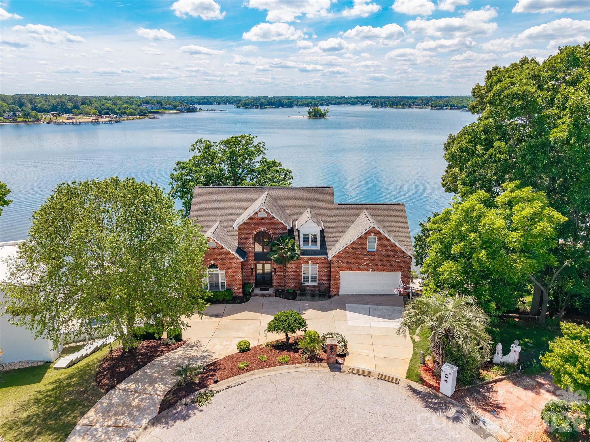 Stunning waterfront retreat on Lake Wylie offering breathtaking main channel views and unforgettable sunsets from nearly every room. Located in Tega Cay, this exceptional 4 bedroom, 3.5 bath home is designed for luxurious lakefront living with panoramic water views greeting you the moment you walk through the front door.
Inside, you’ll find gorgeous architectural details throughout including shiplap walls, vaulted ceilings, beautiful wood ceiling accents, and two impressive stone gas log fireplaces located in the great room and primary suite. The spacious main-level primary suite features a luxury bath and an incredible walk-in closet/dressing room.
Designed for entertaining, the home also includes a bunk room, rec room with kitchenette, and a stunning stone-trimmed bar area. Expansive covered porches and a private balcony provide the perfect place to unwind while taking in the long-range lake views.
Step outside to your own private waterfront oasis featuring a lakeside saltwater pool and spa, covered dock with boat lift, and direct access to the main channel for boating and water recreation. Additional features include a double attached garage, walk-in attic storage, and exceptional indoor and outdoor living spaces that make this lake home truly one of a kind.
