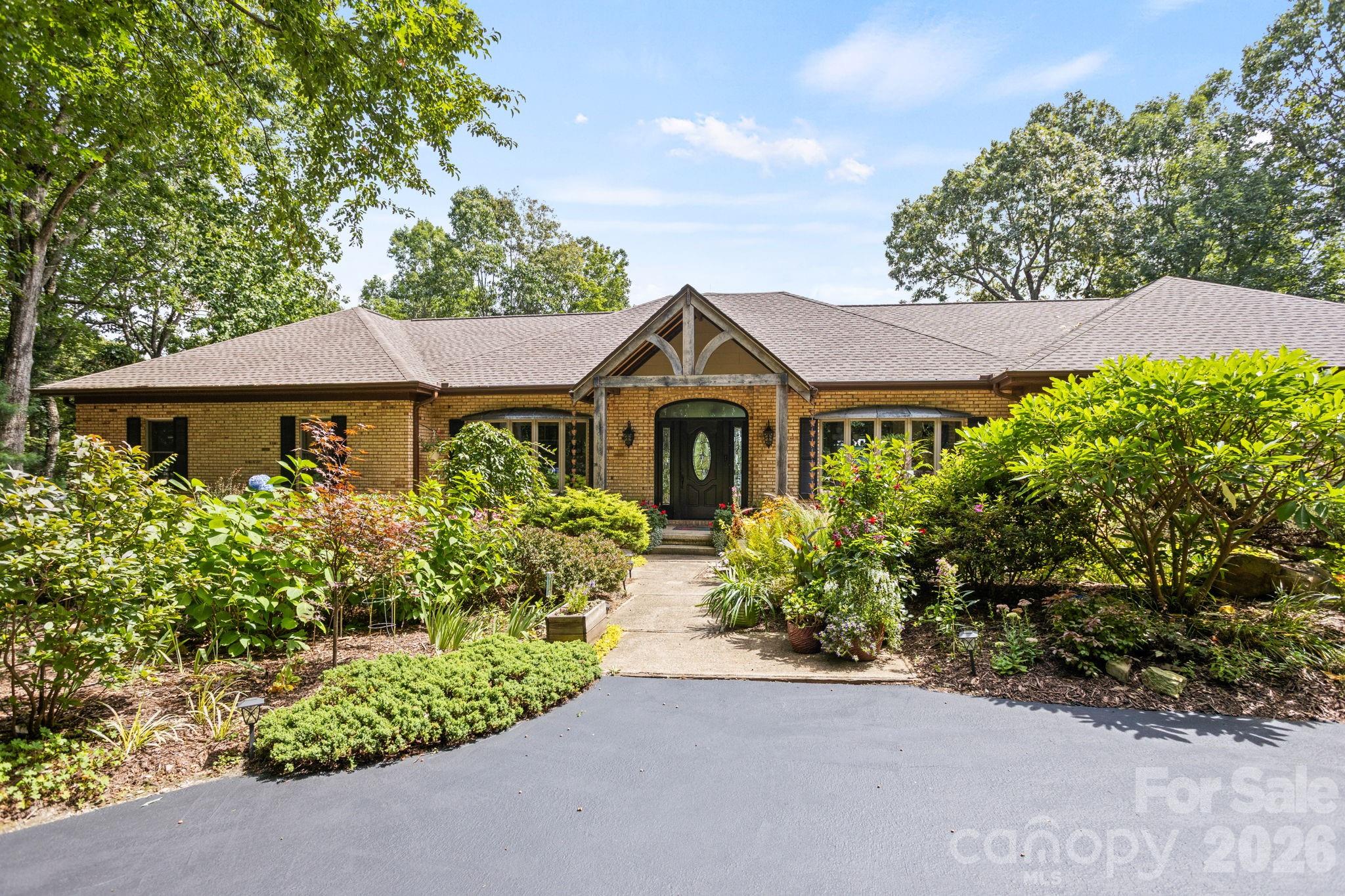 Absolutely stunning and complete transformation and renovation, this exceptional home with mountain views is privately tucked away on over 2 acres of meticulously landscaped grounds in the prestigious gated community of Kenmure. A true gardeners’s paradise, this property features meandering pebble pathways, a serene garden patio and lush, mature landscaping offering privacy, beauty and tranquility. Step inside to discover an amazing open concept and main level showcasing a gourmet chef’s kitchen with high-end stainless steel appliances, an oversized island with prep sink and breakfast bar, pantry, an abundance of cabinetry and counter space for all your culinary adventures. The kitchen opens into a sunlit breakfast room, open dining area and an impressive great room centered around a striking floor to ceiling unique gas fireplace. The huge primary suite is a private retreat featuring plantation shutters, designer walk-in closet and a luxurious spa-like bath with heated tile floors, dual vanities, a unique walk-in waterfall shower and soaking tub. Also on the main level is a guest bedroom and guest bath, a powder room, stunning den/TV room, office/studio and well appointed laundry room with sink and cabinetry. The lower level offers a generous family/game room and huge guest suite with ensuite bath. You will also find ample unfinished storage space for all your needs. Whether you are entertaining on the large screened porch, relaxing on the open deck or enjoying the peaceful garden patio, every corner of this home is designed to embrace the best of luxury mountain living.