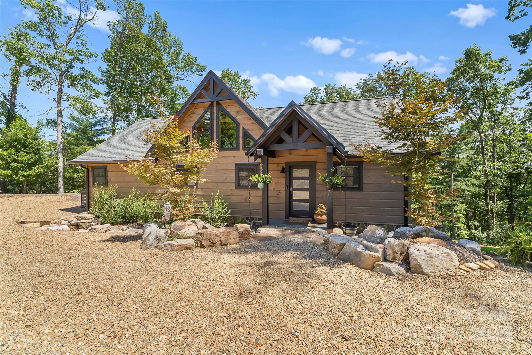 Lake James Gem – Just in Time for Summer. Deeded boat slip, lake views, and seamless indoor-outdoor living—this is Lake James done right. This 4 bedroom 3.5 bathroom lake home is tucked away on 1.41 private acres between two conservation areas, this exceptional home offers the perfect blend of tranquility, mountain charm, and unforgettable lake living. Arrive via a striking rock bridge framed by boulders, setting the tone for the unique experience that awaits. Inside, the main level features a spacious, light-filled great room with exceptional lake views and a stunning two-sided gas fireplace shared with the covered porch—ideal for enjoying cool evenings.
The primary suite on the main level offers a private balcony and serene lake views, creating a peaceful retreat, large closets and custom shower. An additional ensuite bedroom, guest bath, and laundry provide convenience and flexibility for hosting family and friends. A thoughtfully designated, build-ready area for a future 2.5-car garage adds flexibility and long-term value—giving you the option to expand without compromising the home’s natural setting. Designed for entertaining, the lower level is a true gathering space with a large great room, wet bar, wine nook, tin ceiling accents, and stained concrete floors. Two additional bedrooms, a full bath, and a dedicated office make it perfect for extended stays or remote work. Retractable glass doors open to bring the outdoors in—perfect for embracing lake living. Your deeded community boat slip is just a short walk or golf cart ride away, making spontaneous days on the water effortless. As a resident of Camp Lake James, you’ll also enjoy access to luxurious amenities, social events, and a vibrant lake community. This is more than a home—it’s a lifestyle, blending rustic charm with modern comfort and endless opportunities for recreation on one of North Carolina’s most beautiful lakes. Move in just in time for lake season and start making unforgettable memories on Lake James from day one.