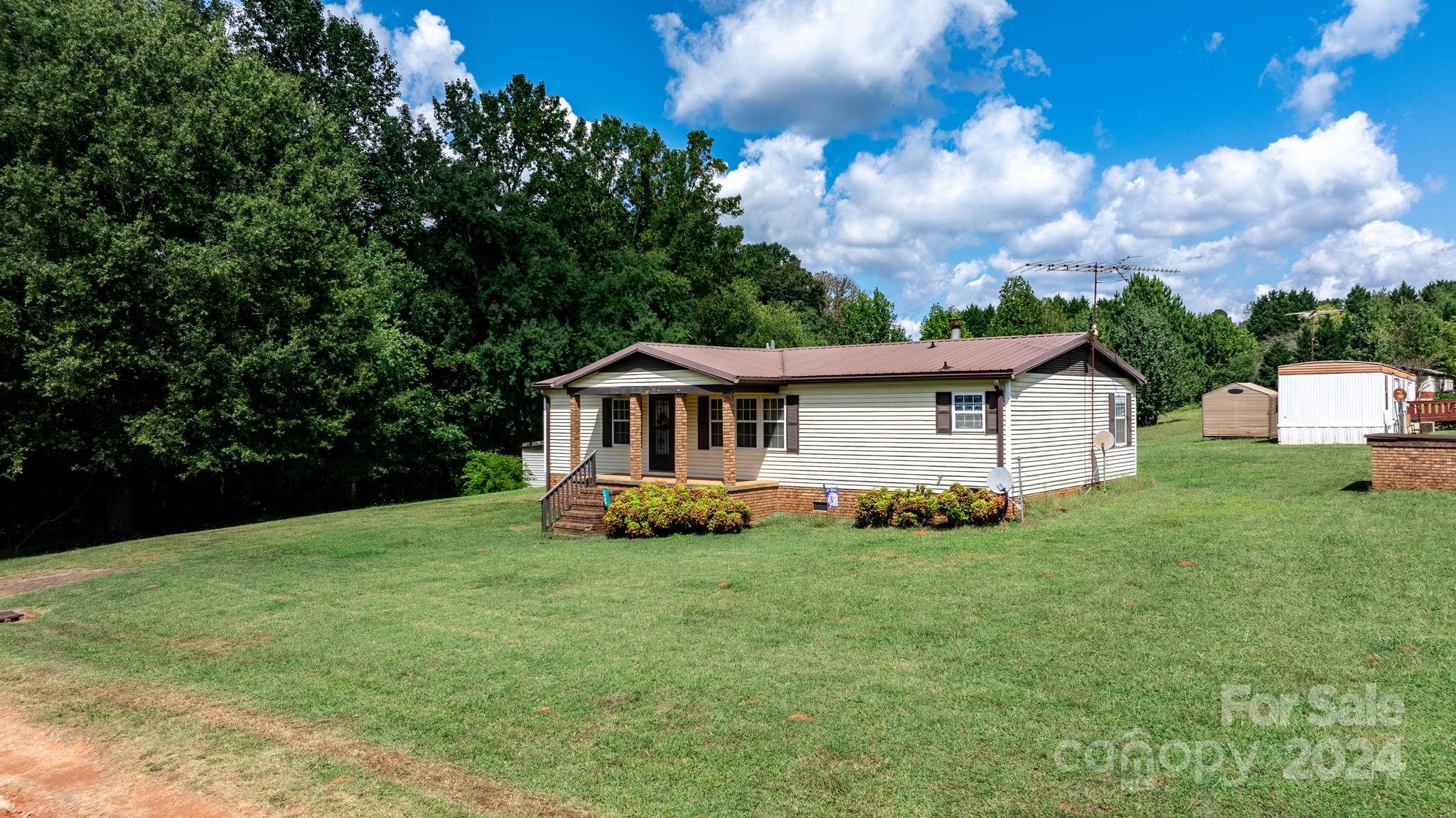 Welcome to 2400 Journeys Pass in Newton, a well-maintained 2-bedroom, 2-bathroom manufactured home that is move-in ready! Situated on a desirable corner lot, this property features both a covered front porch and a rear porch, perfect for relaxing or entertaining. The home also comes with three storage buildings, including a wood structure equipped with electricity—ideal for a workshop or additional storage. Located just a short drive from Fred T. Foard High School, this charming home offers convenience and comfort in a peaceful setting.