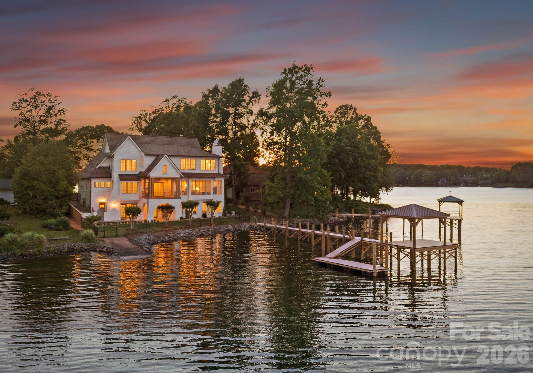 Positioned on one of Lake Norman’s most exceptional waterfront lots, 1884 Hagers Point Lane offers breathtaking long-range main channel views. Thoughtfully designed to maximize the property’s remarkable setting, the residence captures sweeping open-water views from nearly every room. Expansive windows, carefully oriented living spaces, and seamless indoor-outdoor connections create a home deeply connected to its waterfront setting.
A warm, natural material palette defines the home inside and out, with wide-plank natural white oak floors, hardwood trim details, natural marble tile and countertops, limestone porches and pool decking, and a Brava cedar shake roof contributing to a timeless, cohesive design.

The main living area is anchored by a striking fireplace designed for either gas or wood-burning use, while the chef’s kitchen is designed for both everyday living and entertaining with custom cabinetry, premium appliances, marble countertops, and a fully equipped scullery.

The floor plan offers exceptional flexibility, including two luxurious primary suite options. The main-level suite provides convenient first-floor living, while the upstairs primary suite captures incredible lake views from an elevated vantage point. Two additional guest bedrooms, a well-appointed laundry room, and a versatile bonus area complete the upper level.

The walkout basement is designed for entertaining, recreation, and guest accommodations, with a living area, wet bar, dedicated gym space, pool bath, guest suite, fifth full bathroom, and utility closet with a third laundry area. Outdoor living is equally impressive, with professionally designed landscaping, irrigation, a newly constructed dock, and a grandfathered boat ramp.

Thoughtfully integrated systems further enhance daily living, including an Energy Recovery Ventilator for efficient fresh-air circulation, whole-home water filtration, reverse osmosis drinking water treatment, dual tankless water heaters, and pre-wiring for a generator.

Located in the southern portion of Denver, the property offers convenient access to Charlotte, shopping, and restaurants while delivering a private, resort-like setting on one of Lake Norman’s most desirable peninsulas. 1884 Hagers Point Lane is a rare opportunity to own a custom luxury waterfront home where exceptional design, premium materials, and extraordinary views come together in one of the lake’s most compelling waterfront offerings.