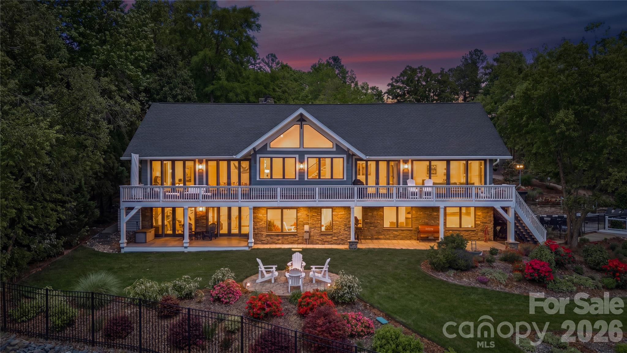 An exceptional gated waterfront estate set on a private 1.35-acre homesite along Lake Wylie’s sought-after main channel, showcasing stunning sunset views and an atmosphere of refined, effortless luxury. Thoughtfully designed with timeless craftsmanship and modern sophistication, this residence captures panoramic water views from nearly every room. The main living spaces are both grand and inviting, defined by soaring vaulted ceilings, rich architectural detailing, and seamless indoor-outdoor flow. A beautifully appointed great room with custom built-ins and fireplace flows seamlessly into the chef’s kitchen, newly updated in 2026—an elegant yet highly functional space featuring marble countertops, an oversized island, walk-in pantry, and a full suite of professional-grade appliances, including a Wolf gas cooktop, steam oven, and Thermador refrigerator. Refined entertaining continues in the formal living and dining rooms, complete with a wet bar—ideal for intimate gatherings or elevated hosting. The primary suite serves as a private sanctuary, offering dual custom closets, a spa-caliber bath with heated floors, and the convenience of an adjoining laundry. The lower level is designed for both relaxation and hosting, featuring an expansive recreation room, a warm and inviting den with wet bar and direct access to the pool and patio.  Three additional bedrooms each with an ensuite bathroom are elegantly appointed for comfort and privacy. There is even a secondary laundry space for guests and pool towels. A spacious three car garage also features tons of storage above.  Outdoors, the property transforms into a true resort-style retreat. A sprawling composite deck, covered terrace, and meticulously landscaped grounds surround a saltwater pool and spa, creating an atmosphere of serene leisure. The private covered dock with boat lift provides immediate access to the lake, completing this rare offering. A distinguished waterfront residence just moments from Charlotte, delivering an unparalleled blend of privacy, design, and lakefront living.