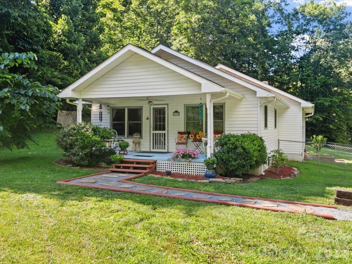 Welcome to this storybook cottage nestled on a beautiful open 1.14-acre unrestricted lot in the Green Mountain community of Yancey County. From the moment you arrive, the inviting covered front porch and the soothing sounds of the property's small natural stream create a serene escape. Inside, the 1,534-square-foot main level seamlessly blends classic 1940s character with modern functionality, featuring 3 comfortable bedrooms, two and a half bathrooms with warm wood flooring throughout the living spaces. The light filled kitchen flows into the spacious dining room, while a dedicated main level laundry room adds everyday convenience. Step out onto the expansive back deck-ideal for dining, relaxing, or taking in the beautiful landscape. Additional highlights include new energy-efficient ductless mini-split systems for climate control, a spacious walk-out unfinished partial basement perfect for a workshop or storage and a publicly maintained road for easy year-round access. This property offers a wonderful balance of peaceful country living and functional design. Short drive to public access on the beautiful North Toe River for a day of fishing, tubing or kayaking. 20 minute drive to downtown Burnsville, 45 minutes to Johnson City TN or 1 hour to Asheville. Showings by APPOINTMENT ONLY!