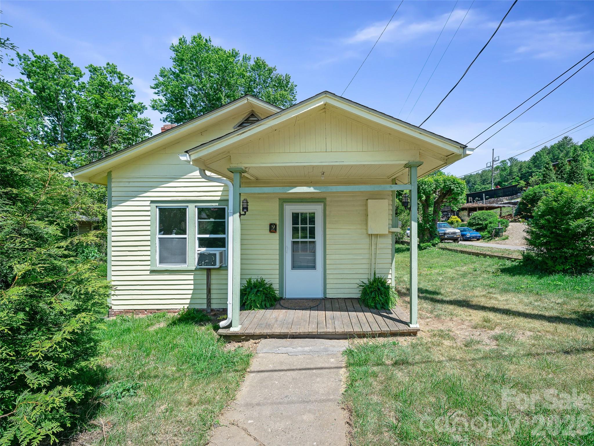 Charming in-town cottage with endless possibilities in the heart of downtown Burnsville, NC UNDER $200K! Built in 1920, this unique property blends vintage character with flexible C-3 zoning for residential or commercial use. The home needs additional TLC, but is move-in ready and features a spacious updated kitchen and dining area, living room, 2 bedrooms (one with closet), renovated full bathroom, and a small sunroom/laundry area with washer and dryer included. Beautiful pinewood floors have been freshly painted, creating a bright and inviting interior. Recent improvements include new storm doors, new insulated windows, a new hot water heater, and a propane Rinnai monitor heater. Situated on a level corner lot fronting both East Blvd and Ivy Street, the property offers excellent accessibility and visibility. Approximate lot size is 0.14 +/- acres with city water and sewer. Perfect opportunity for a starter home, rental, art studio, boutique, office space, or small business. Lot of opportunity for additional improvements or enjoy as-is. Enjoy being just a short walk 0.25 mile walk to Burnsville’s charming Town Square, local restaurants, coffee shops, galleries, and shopping. Burnsville is known for its vibrant downtown, mountain-town charm, and thriving arts community. Whether you're looking for a cozy residence, investment opportunity, or business location, this property offers outstanding potential in one of Western North Carolina’s most desirable small towns.