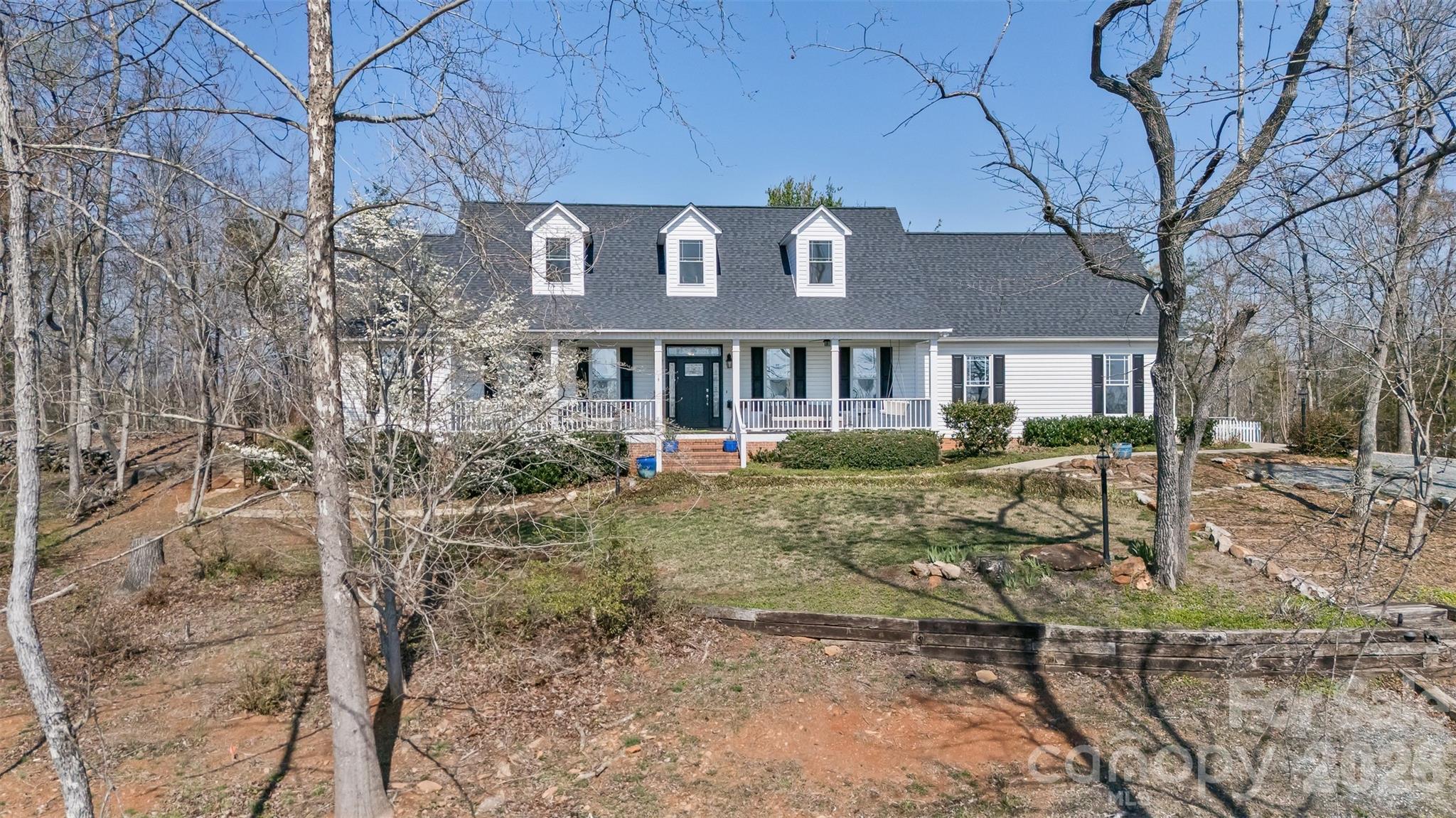 YOU HAVE TO SEE IT TO BELIEVE IT!! Look no further for a wonderful combination of serene beauty and equine functionality! The maple-lined driveway leads you up to the spectacular main house. The views here provide a breathtaking landscape as this unique property rests at the top of a hill. Evening sunsets against mountains provide awe-inspiring visuals as you relax on the outdoor seating areas. The main house has vaulted ceilings, hardwood floors and luxury vinyl plank in the laundry room and bathrooms. Ample windows in each room provide wonderful natural light throughout this home. Spacious two car garage with closets and built in cabinets provide excellent storage and functionality. Includes built in gym features that can be folded away to maximize flexibility in the space. Bedroom layouts provide an array of options, including a second ensuite from the owner’s suite that is complete with a wide handicapped-accessible shower. House is arranged with bedrooms spread out with the kitchen, dining, and living rooms arranged in a central gathering hub. The kitchen is complete with high end appliances and thoughtful cabinetry features for your culinary needs. Elegant dining room with built in bar is perfect for those large gatherings. Just off the kitchen, there is a small step-down library/sunroom where you can sit and pause to enjoy the surroundings. Working from home? The home office affords a magnificent blend of productivity and scenery! Walk upstairs to find a large seating area complete with a full bathroom of its own. From this space, walk right into a cavernous (and easily accessed) walk-in attic (also continuing the natural light theme of this wonderful house!) with tremendous amounts of storage for your seasonal decorations or whatever treasures you might have. Large front and back porches adorn the home enable spots for reflection and absorbing the natural beauty of the property. The backyard provides a grassy area with surrounding stone path, a two-level trellis deck, and a darling garden shed capable of housing gardening and yard maintenance equipment, with a greenhouse tacked on for your potting needs! Want to enjoy the starry nights? Gather around the backyard firepit and make lasting memories! Got a green thumb? Enjoy an amazing raised-bed garden encompassed by a white picket fence. So, we mentioned horses – WOW! Property includes a newly renovated two-story barn, complete with two fully functional stables, temperature-controlled tack room, and half bath. Upstairs there is a newly added and fully permitted studio apartment/guest house with full kitchen, washer/dryer hookups, and a full bathroom. This barn affords an array of possibilities! Across the driveway you will find two fully fenced paddocks complete with run-ins. A path runs around the entire property, allowing a stroll for you and any number of four-legged friends. The Collinsville Equestrian Trail Authority (CETA) trails are nearby. Property is located 15 minutes from the Tryon International Equestrian Center. Multiple parking options exist on the property, including spaces or any trailers you might have. Check out the aerials/drone footage! NOTE: An extensive list of features, renovations, and upgrades is included as an attachment in this listing and available upon request. Co-listing agent is an owner.