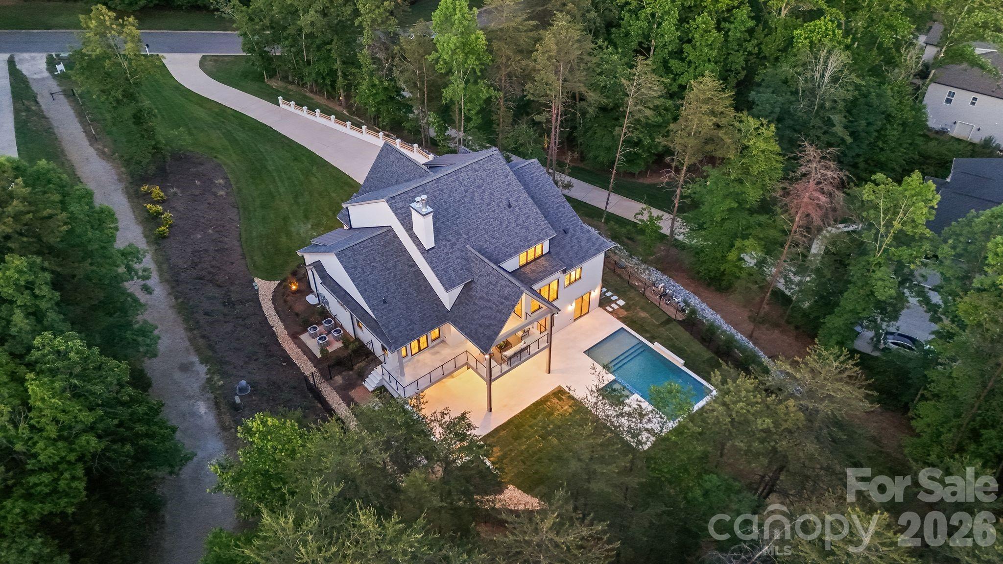 A home like no other — professionally designed, expertly executed, and crafted to deliver an exceptional luxury lifestyle on Lake Norman. From the moment you arrive, the estate presence is undeniable. A long private driveway leads to this striking custom hard stucco residence accented with black Andersen windows and timeless architectural design that immediately sets the tone for what awaits inside.

Offering over 6,100 square feet, this home was thoughtfully curated with elevated finishes, refined details, and spaces designed for both everyday living and unforgettable entertaining. Beautiful flooring flows throughout the main level, drawing you into the stunning living room anchored by a soaring designer fireplace that serves as the centerpiece of the home.

The custom kitchen is truly magazine-worthy, featuring two-tone cabinetry, cabinet-front appliances, Taj Mahal quartzite, an oversized island, walk-in pantry, and adjoining wet bar designed for seamless hosting. A massive laundry and utility room provides exceptional storage and functionality without sacrificing style.

Step outside onto the vaulted covered deck and experience breathtaking views of your private backyard retreat complete with a pool, expansive patio space, and beautiful views of Lake Norman. Every detail was designed to maximize indoor-outdoor living and create the perfect setting for entertaining or quiet evenings overlooking the water.

The primary suite is a private sanctuary featuring direct deck access and a spa-inspired wet room with a freestanding soaking tub and oversized walk-in shower. Upstairs, an open loft overlooks the main living area below while additional bedrooms and custom baths provide comfort and privacy for family and guests.

While permitted for 4 bedrooms, the home offers a total of 7 rooms, allowing incredible flexibility for guest accommodations, offices, fitness spaces, hobby rooms, or additional living areas.

The basement level is where this home truly comes alive. Designed for entertaining on every level, the space is ready for a theater/media room, billiards area, poker lounge or speakeasy, home gym, or even a secondary living quarters complete with space for a full kitchen. Walk-out access leads directly to the pool and patio, making entertaining effortless year-round. A basement garage offers ideal storage for a golf cart, lake toys, or recreational equipment.

To complete the experience, the property includes a deeded boat slip directly behind the home — making sunset cruises and spontaneous days on Lake Norman part of everyday life.

This is more than a home. It is a statement property designed for those who want luxury, lifestyle, and unforgettable lake living.