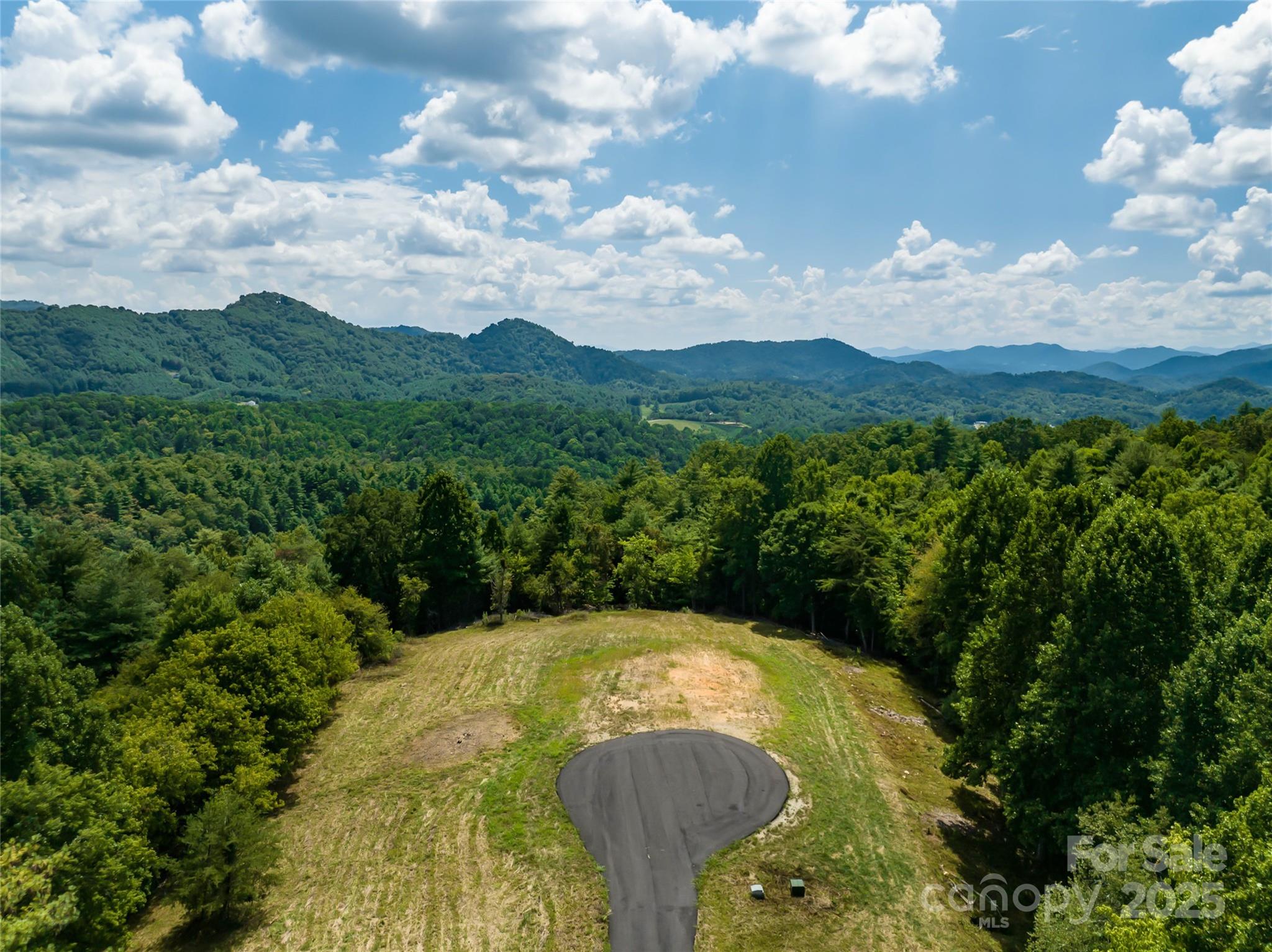 Private yet easily accessible, this exceptional 7.25-acre homesite in the gated community of French Broad Crossing offers sweeping mountain views and a gentle, cul-de-sac setting—ideal for an easy build. Perfectly positioned near the entrance for added convenience, this lot is a rare find within one of Western North Carolina’s premier conservation communities. Residents enjoy exclusive access to world-class amenities including a timber-framed River Lodge, wellness center, pool, riverfront park, pavilion, hiking trails, and more. Just 8 miles from Marshall and 30 scenic minutes to downtown Asheville, this homesite is the perfect canvas for your custom mountain retreat. Experience the best of privacy, natural beauty, and refined adventure in one unforgettable location.