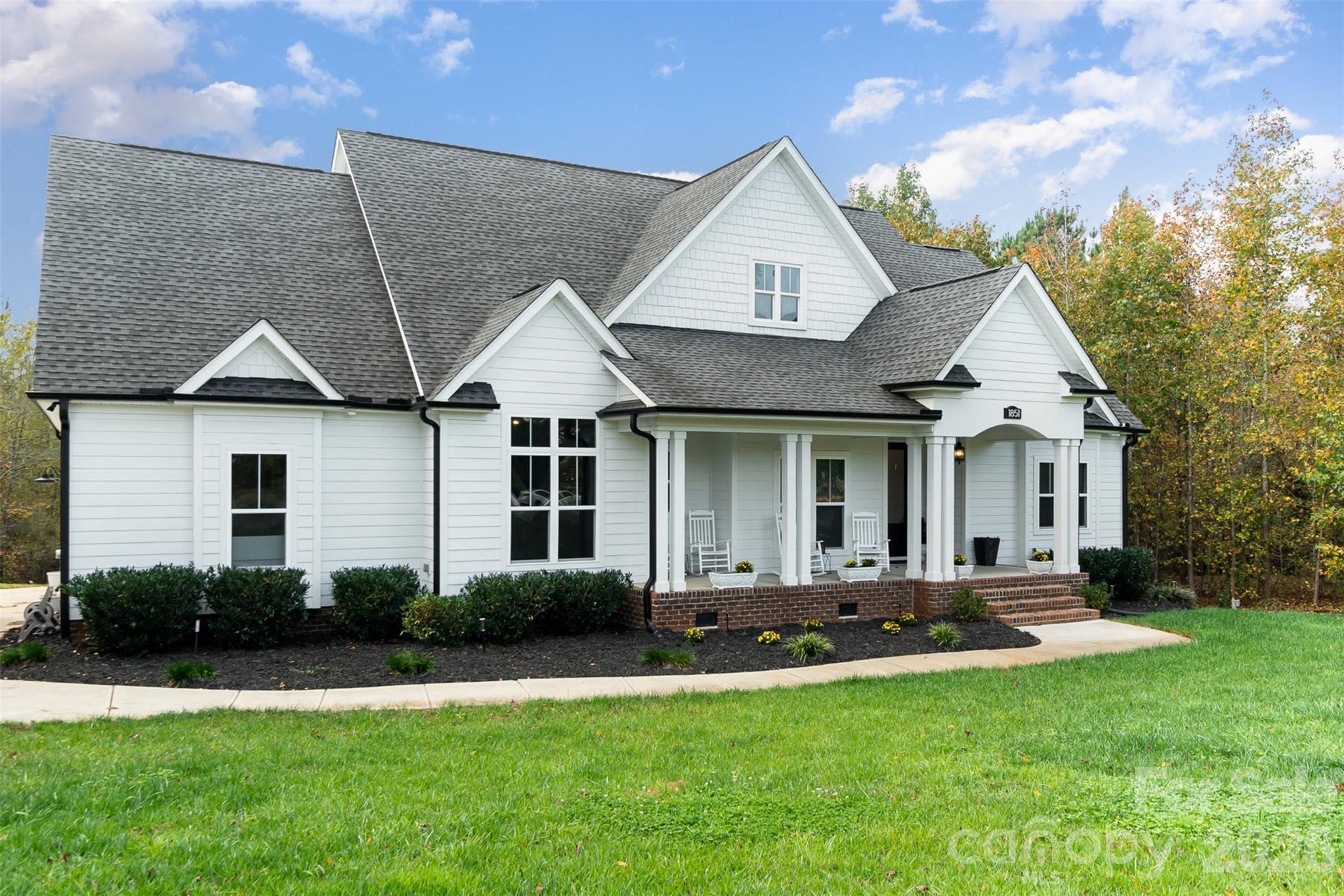 Welcome to Catawba Shores Estates, where refined craftsmanship meets peaceful, upscale living on a private 1-acre wooded homesite. This stunning 4 bedroom, 3 bathroom residence offers a thoughtfully designed layout paired with high-end architectural details and a seamless indoor-outdoor lifestyle.

From the moment you arrive, the rocking chair front porch sets the tone for relaxed Southern elegance. Inside, the open-concept design is enhanced by coffered ceilings, tray ceilings, custom wainscoting, and dramatic floor-to-ceiling windows that flood the living space with natural light. The main living area flows effortlessly into a chef-inspired kitchen anchored by an oversized island, ideal for entertaining and everyday luxury.

The main-level primary suite is a true retreat, featuring a spa-like bathroom with a walk-in tile shower, soaking tub, and dual walk-in closets, offering both comfort and sophistication. Upstairs, a private fourth bedroom or bonus suite provides exceptional flexibility, complemented by extensive walk-in attic storage.

Step outside to a covered rear porch overlooking a professionally designed fire pit area, surrounded by mature trees that create a sense of privacy and serenity—perfect for quiet evenings or hosting guests.

Residents of Catawba Shores Estates enjoy access to resort-style amenities, including a community pool, scenic walking trails, and direct paddleboard/kayak launch access to the Catawba River, delivering a lifestyle rarely found at this price point.

Ideally located just 15 minutes from Rock Hill’s premier shopping, dining, and conveniences, this home offers the perfect balance of luxury, privacy, and accessibility.

An exceptional opportunity to own a designer-quality home with acreage in one of the area’s most desirable lifestyle communities.