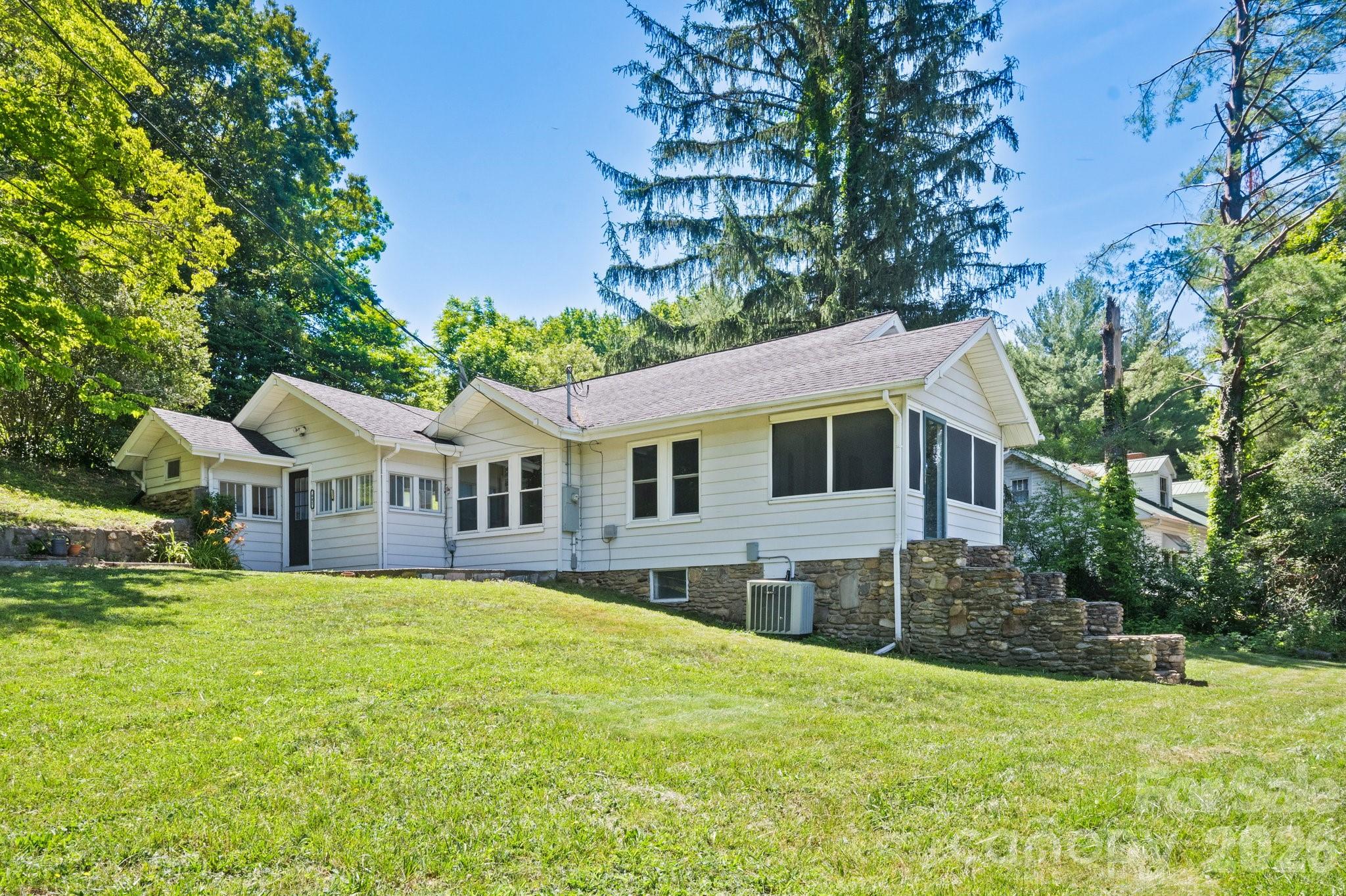 Enjoy the sun set from the screened in porch!  This charming cottage-style home offers a rare combination of character, convenience, and acreage. Situated on approximately .64 acres, the property features a spacious yard with mature trees.
Inside, you'll find original beadboard ceilings, original hardwood floors, abundant natural light, and a welcoming stone fireplace that serves as the focal point of the living room. The home offers a functional layout with a dedicated dining room, spacious kitchen, screened porch, and generously sized bedrooms. The screened-in porch is the perfect place to enjoy your morning coffee while taking in the mountain scenery and cool mountain breezes
Outside provides plenty of room for gardening or outdoor entertaining on the patio. A covered carport offers convenient parking. Minutes from downtown Clyde, Waynesville, shopping, dining, and I-40.
Whether you're searching for a full-time residence, mountain retreat, or investment opportunity, this property offers tremendous potential in a picturesque Western North Carolina setting.
Some photos have been virtually staged to illustrate the property's potential.