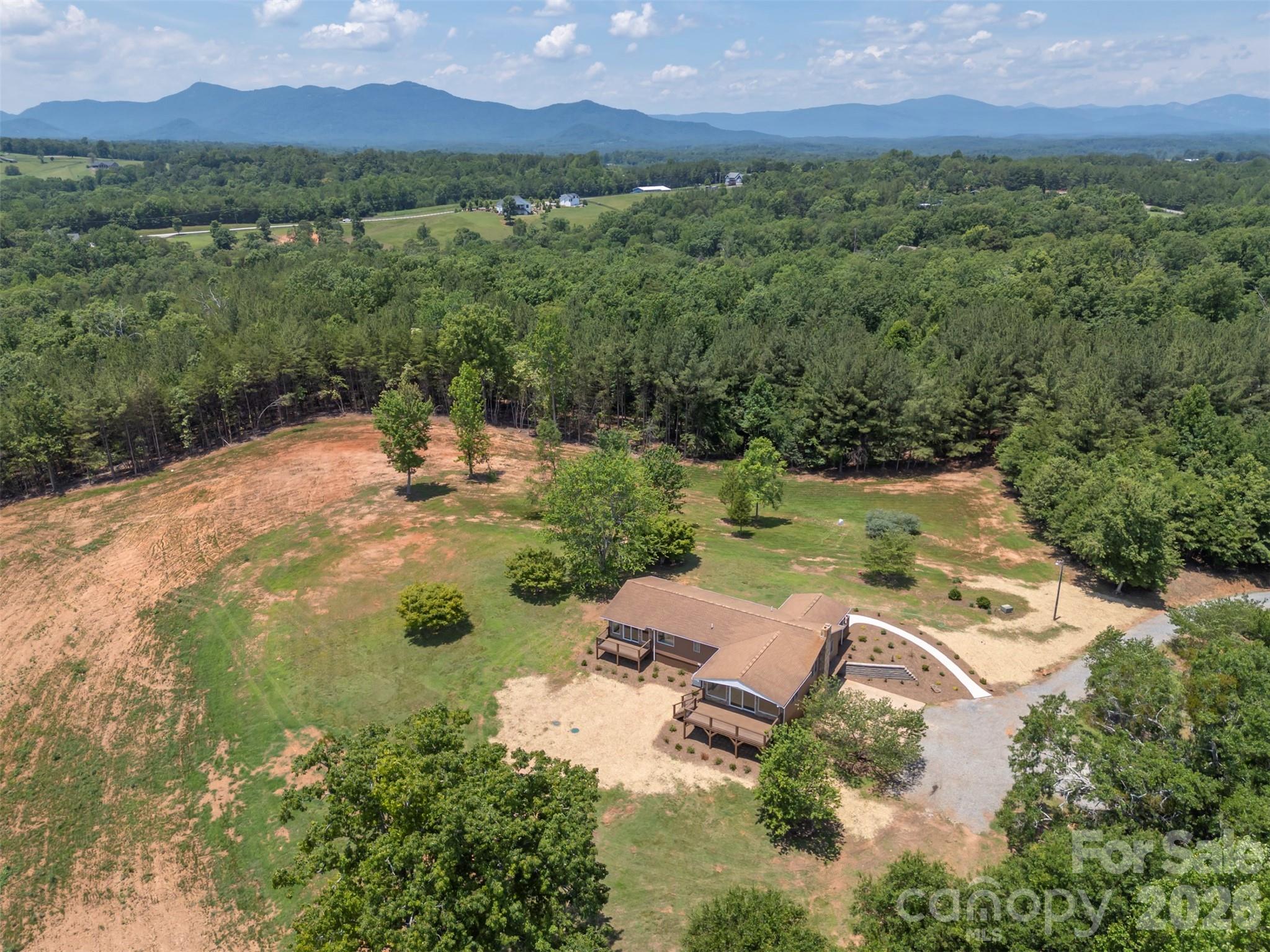 Escape to your own private hobby farm up a long driveway off Highway 9 on 10.09 unrestricted acres, with direct access to the CETA trail system right outside your door. Here, single-level living meets total peace of mind — bring your animals, your hobbies, and your vision, with no covenants or restrictions to hold you back. The home is bright, with large windows and sliding doors that let light and the long-range views in. The dining room/sun room has vaulted ceilings, and so does the main bedroom. The main bedroom also features an extra-large walk-in closet, a new south-facing deck, and its own bathroom with a washer/dryer hook-up. 
This home has been extensively and thoughtfully updated throughout, starting with the major systems: a new septic system, a new Armstrong heat pump HVAC system, all new plumbing and lighting fixtures, a new hot water heater, a new foundation block wall beneath the dining area, and fresh insulation under the dining room, primary suite, and foyer. The full basement has been completely waterproofed and offers abundant storage, a half bath, and a charming old woodstove for cozy nights in and a new French-door walkout to the yard.
Inside, you'll find a beautifully renovated tile-and-glass shower, new LVP flooring in the guest bedrooms, and fresh interior paint throughout. Outdoors, the property has been just as carefully refreshed, with three brand-new decks and handrails, a new retaining wall, fresh landscaping, and a new sidewalk leading to the home. A fully updated shed — with new siding, paint, and shingles — rounds out the package. 
Two additional acres have been cleared, offering plenty of room to roam, garden, or raise animals, while mature blueberry bushes are already established and ready for next season's harvest — chickens optional, but highly recommended. Spend your evenings on one of three decks, watching the kids and dogs play across your own private acreage, or set out on the CETA trail right from home.
Despite the seclusion, convenience is never far away: a store is just one minute from your driveway, and both I-74 and I-26 are within a ten-minute drive for an easy commute.