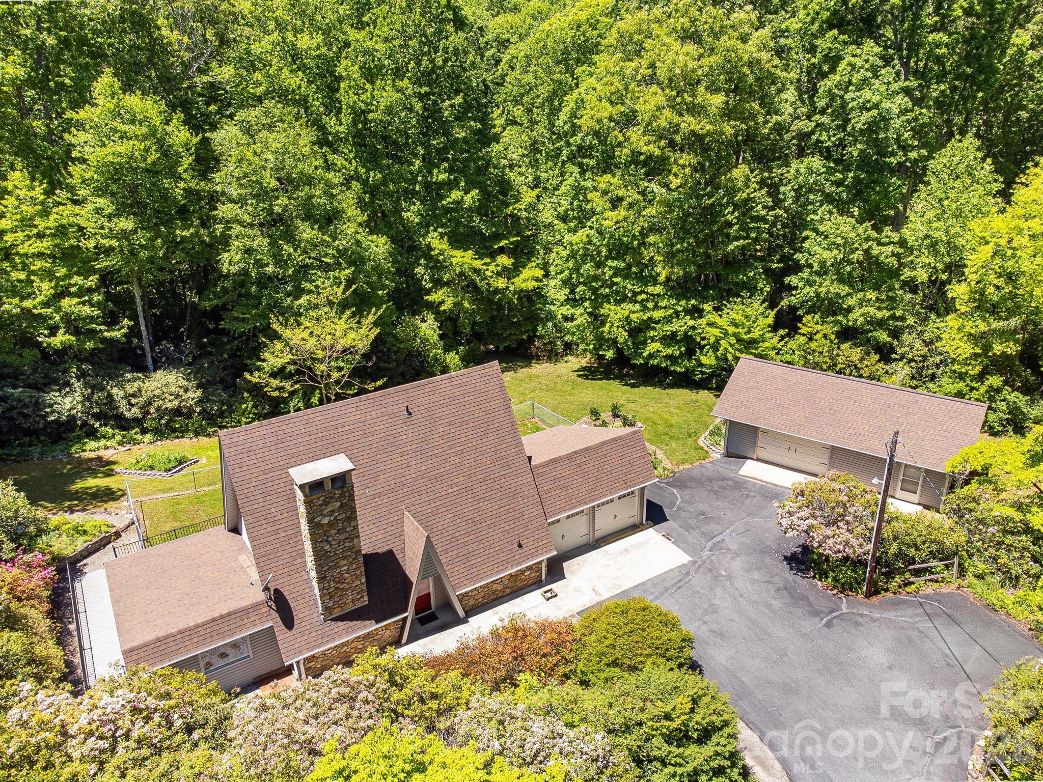 Tucked away on nearly 5 private acres in the heart of Fairview, this one-of-a-kind A-frame retreat offers the perfect blend of character, space, and versatility — whether you’re looking for a primary residence, a mountain getaway, or a high-performing short-term rental.

The striking exterior immediately sets this home apart, featuring a dramatic A-frame roofline, a soaring stone chimney, and a stone foundation that anchors the home beautifully into its wooded surroundings. An attached two-car garage, a detached two-car garage with a workshop — which could potentially be finished out as an additional dwelling unit — and a large deck with black iron railings round out an exterior that’s as functional as it is impressive.

Inside, the home has been freshly updated throughout including new paint, new countertops, and new flooring. The main living areas center around a stunning floor-to-ceiling stone fireplace, with exposed wood beams, an open floor plan, and an abundance of windows that frame the beautifully landscaped surroundings at every turn.

The kitchen features stainless LG appliances and the updated bathroom showcases a beautifully tiled walk-in shower with modern fixtures. Two bedrooms offer serene tree-lined views, and the flexible layout also includes a bonus room with a closet — perfect as a home office or additional sleeping quarters for guests.

Step outside and explore trails cut throughout the property, offering a private escape into the natural beauty that makes this setting truly special. Additional highlights include a whole-home generator — a must-have for mountain living. The nearly 5-acre lot is a rare find in Fairview — completely private, tree-canopied, and just minutes from Black Mountain and a short drive to downtown Asheville.

Properties like this don’t come along often. Schedule your showing today!