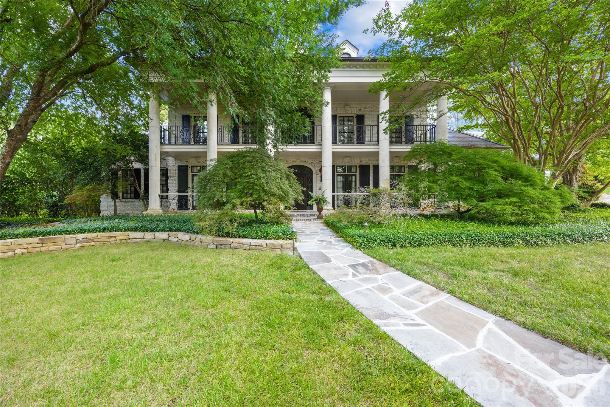 Located in the prestigious gated community of Morrocroft Estates, known for its luxurious custom homes on expansive estate-sized lots. This stunning French Country estate on 1.2 acres begins with the stone-lined driveway leading to the side-entry 4-car garage. The home has an elegant double veranda complete with limestone columns, gas lanterns, and a grand double-door entry that opens into an impressive 2-story foyer with a curved staircase. Luxurious details throughout, such as refined moldings, beautiful heart-pine flooring, intricate painting details, a dining room featuring a brilliant Art Nouveau mural alongside an elegant fireplace, and a library with a warming fireplace, built-in cabinets, and a coffered ceiling. The spa-like primary suite is a luxurious retreat featuring a spacious bedroom with a cozy sitting area overlooking the pool. Abundant storage in the dual closets, an elegant soaking tub, and a luxurious steam shower offer a serene retreat for relaxation and rejuvenation. The gourmet kitchen and inviting sitting room with another fireplace enhance the home's comfort. The great room captivates with a coffered ceiling, intricate molding, wrought-iron details, and a grand fireplace, creating a sophisticated atmosphere. Also featured is a spacious guest suite on the main floor, complemented by four bedrooms, each with en-suite bathrooms, and a bonus room on the upper level. Ideal for entertainment, the home boasts five fireplaces and a third-floor media room, decorated with movie-themed murals. Outdoor amenities include a saltwater pool, a travertine patio, and a beautifully landscaped backyard, perfect for gatherings and leisure activities. This property seamlessly combines luxury and comfort, making it an ideal retreat for both relaxation and entertaining guests.