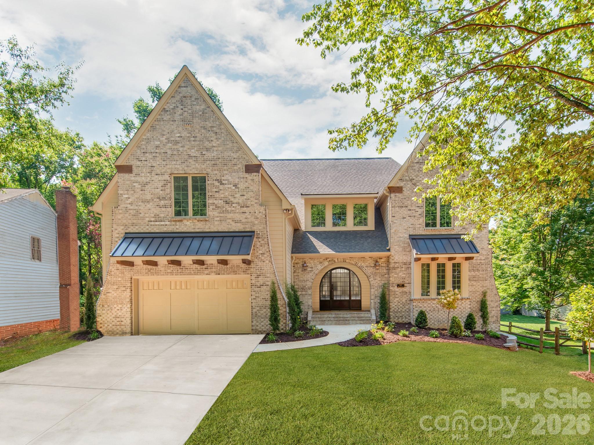 Some of Charlotte's most remarkable homes aren't found on grand boulevards—they're discovered on quiet, tree-lined streets where timeless neighborhoods and exceptional craftsmanship come together. Tucked beneath a canopy of mature trees, this exceptional custom-built home offers over 4,800 square feet with 6 bedrooms, 5 full baths, a luxurious main-level primary suite, and a private study with an adjacent full bath that easily serves as a guest suite. Ideally located just minutes from SouthPark, Park Road Shopping Center, and Uptown Charlotte, this home offers an exceptional blend of luxury, comfort, and convenience. Every finish was selected with purpose, creating a home that feels both timeless and inviting from the moment you walk through the front door. Architectural details—including graceful arched openings, exposed wood beams, curved corners, 5-inch white oak hardwood flooring throughout both levels, built-in bookcases, and extensive custom cabinetry—reflect a level of craftsmanship rarely found in today's new construction. Designed for both everyday living and entertaining, the chef's kitchen features a 48-inch GE Monogram gas range, built-in refrigerator, expansive island, butler's pantry, and a well-equipped scullery. The great room opens seamlessly to the covered outdoor living area, where a tongue-and-groove ceiling and gas fireplace create a natural extension of the home. A second gas fireplace anchors the great room, while extensive custom cabinetry continues throughout the kitchen, scullery, butler's pantry, drop zone, great room, laundry room, and primary suite. The main-level primary suite offers exposed wood beams, custom walnut cabinetry, dual walk-in closets, a spa-inspired bath with soaking tub and oversized shower, plus a convenient stackable washer/dryer location. Upstairs offers four additional bedrooms, a bonus room, and a well-appointed laundry room with custom cabinetry and utility sink. Additional highlights include a 695-square-foot garage, designer tile throughout, CAT6 wiring in the bedrooms, study, great room, and covered porch, surround sound wiring in the great room, kitchen, bonus room, and covered porch, an insulated crawl space with dehumidifier, and a fully fenced backyard with a six-foot privacy fence. Dedicated 50-AMP Circuit for EV Charger (Charger not included). Timeless craftsmanship. Thoughtful design. A home best experienced in person. *Front door to be installed as pictured on or before July 17, 2026.
