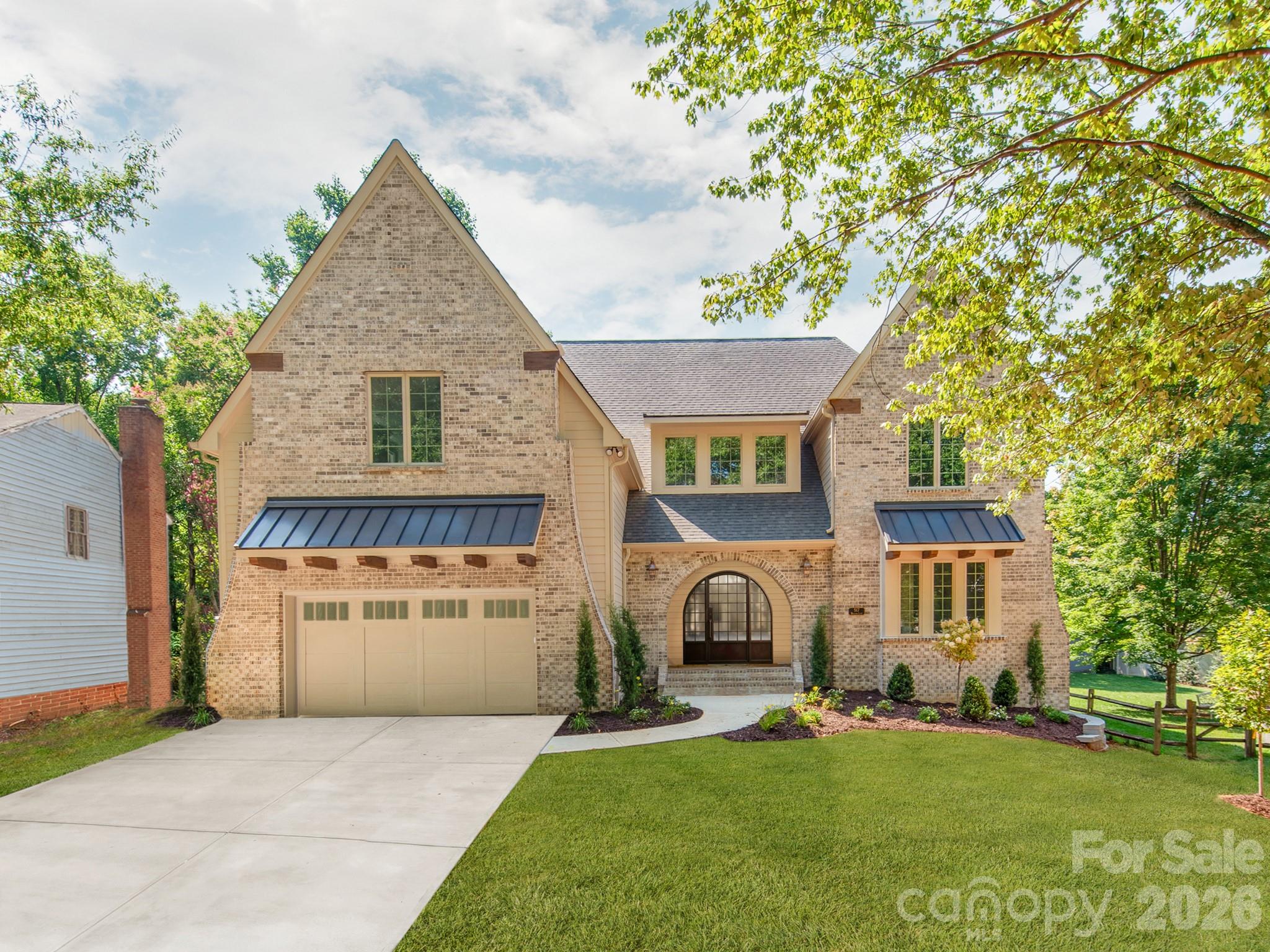Some of Charlotte's most remarkable homes aren't found on grand boulevards—they're discovered on quiet, tree-lined streets where timeless neighborhoods and exceptional craftsmanship come together. Tucked beneath a canopy of mature trees, this exceptional custom-built home offers over 4,800 square feet with 6 bedrooms, 5 full baths, a luxurious main-level primary suite, and a private study with an adjacent full bath that easily serves as a guest suite. Ideally located just minutes from SouthPark, Park Road Shopping Center, and Uptown Charlotte, this home offers an exceptional blend of luxury, comfort, and convenience. Every finish was selected with purpose, creating a home that feels both timeless and inviting from the moment you walk through the front door. Architectural details—including graceful arched openings, exposed wood beams, curved corners, 5-inch white oak hardwood flooring throughout both levels, built-in bookcases, and extensive custom cabinetry—reflect a level of craftsmanship rarely found in today's new construction. Designed for both everyday living and entertaining, the chef's kitchen features a 48-inch GE Monogram gas range, built-in refrigerator, expansive island, butler's pantry, and a well-equipped scullery. The great room opens seamlessly to the covered outdoor living area, where a tongue-and-groove ceiling and gas fireplace create a natural extension of the home. A second gas fireplace anchors the great room, while extensive custom cabinetry continues throughout the kitchen, scullery, butler's pantry, drop zone, great room, laundry room, and primary suite. The main-level primary suite offers exposed wood beams, custom walnut cabinetry, dual walk-in closets, a spa-inspired bath with soaking tub and oversized shower, plus a convenient stackable washer/dryer location. Upstairs offers four additional bedrooms, a bonus room, and a well-appointed laundry room with custom cabinetry and utility sink. Additional highlights include a 695-square-foot garage, designer tile throughout, CAT6 wiring in the bedrooms, study, great room, and covered porch, surround sound wiring in the great room, kitchen, bonus room, and covered porch, an insulated crawl space with dehumidifier, and a fully fenced backyard with a six-foot privacy fence. Dedicated 50-AMP Circuit for EV Charger (Charger not included). Timeless craftsmanship. Thoughtful design. A home best experienced in person. *Front door to be installed as pictured on or before July 17, 2026.