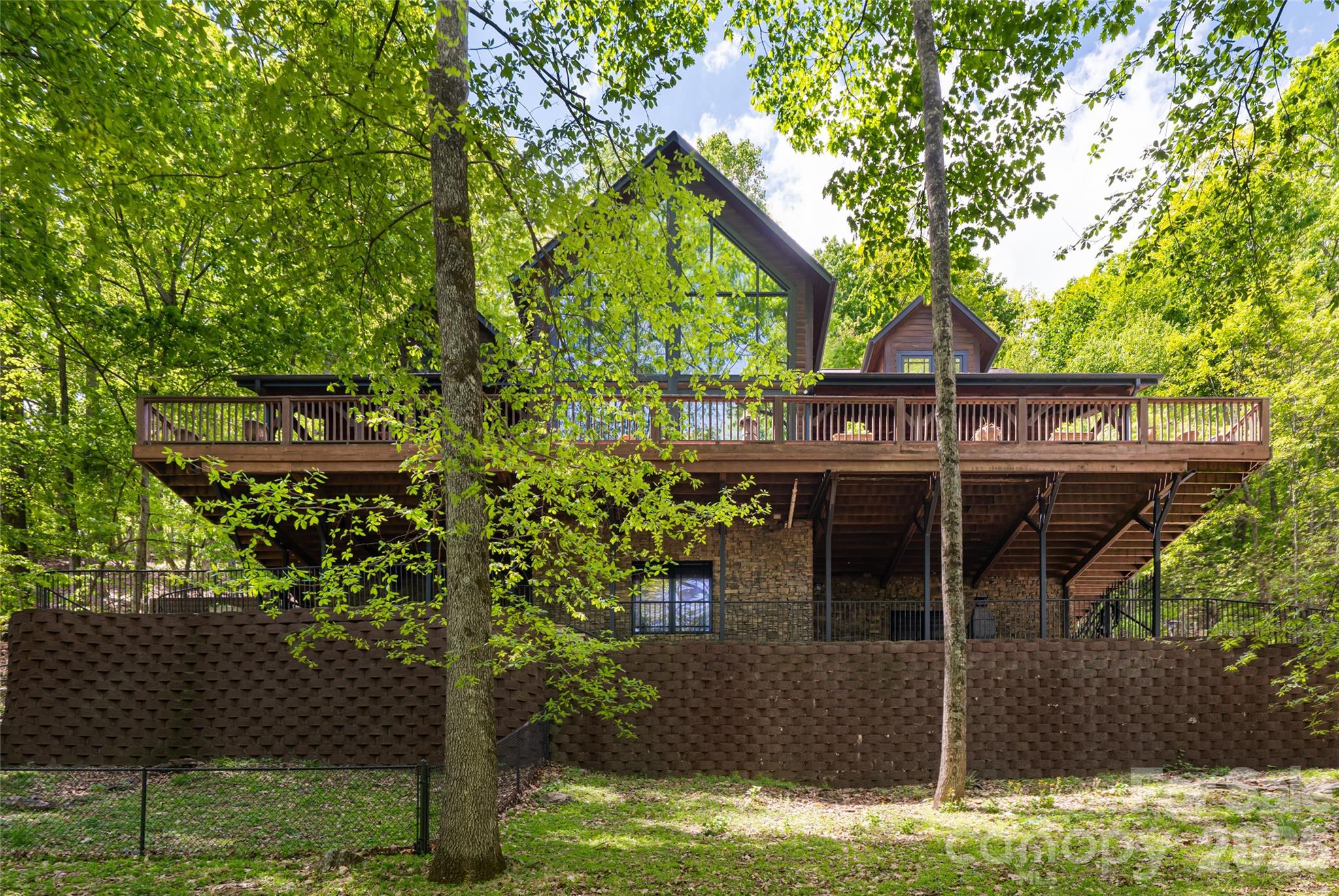 Perched in the sought-after High Vista community of Mills River, this exceptional mountain retreat captures the essence of refined living, where elevation meets breathtaking, long-range views. Designed across three levels plus a fully appointed basement, the home unfolds with graceful intention, each space opening to expansive porches on the top three floors, ideally framing the ever-changing landscape. Inside, exquisite woodworking and bespoke cabinetry create a warm yet sophisticated ambiance. The gourmet kitchen is a centerpiece, appointed with Sub-Zero appliances, a wine refrigerator, wet bar and generous breakfast bar, ideal for intimate mornings and elegant entertaining. The living room is bathed in natural light, its vaulted ceilings enhancing the sense of openness and connection to the surrounding beauty. The primary suite, thoughtfully positioned on the main level alongside the kitchen, dining, living and laundry, offers a private sanctuary with a spa-inspired bath and stunning panoramic views. Upstairs, two additional bedrooms and a lofted office provide flexibility, while the third level reveals inviting bonus spaces for recreation or retreat. The lower level presents a remarkable opportunity for guest living with private entrance and direct access to a serene patio. Outdoors, meticulously designed spaces invite relaxation and gathering, creating a seamless harmony between luxury and nature.