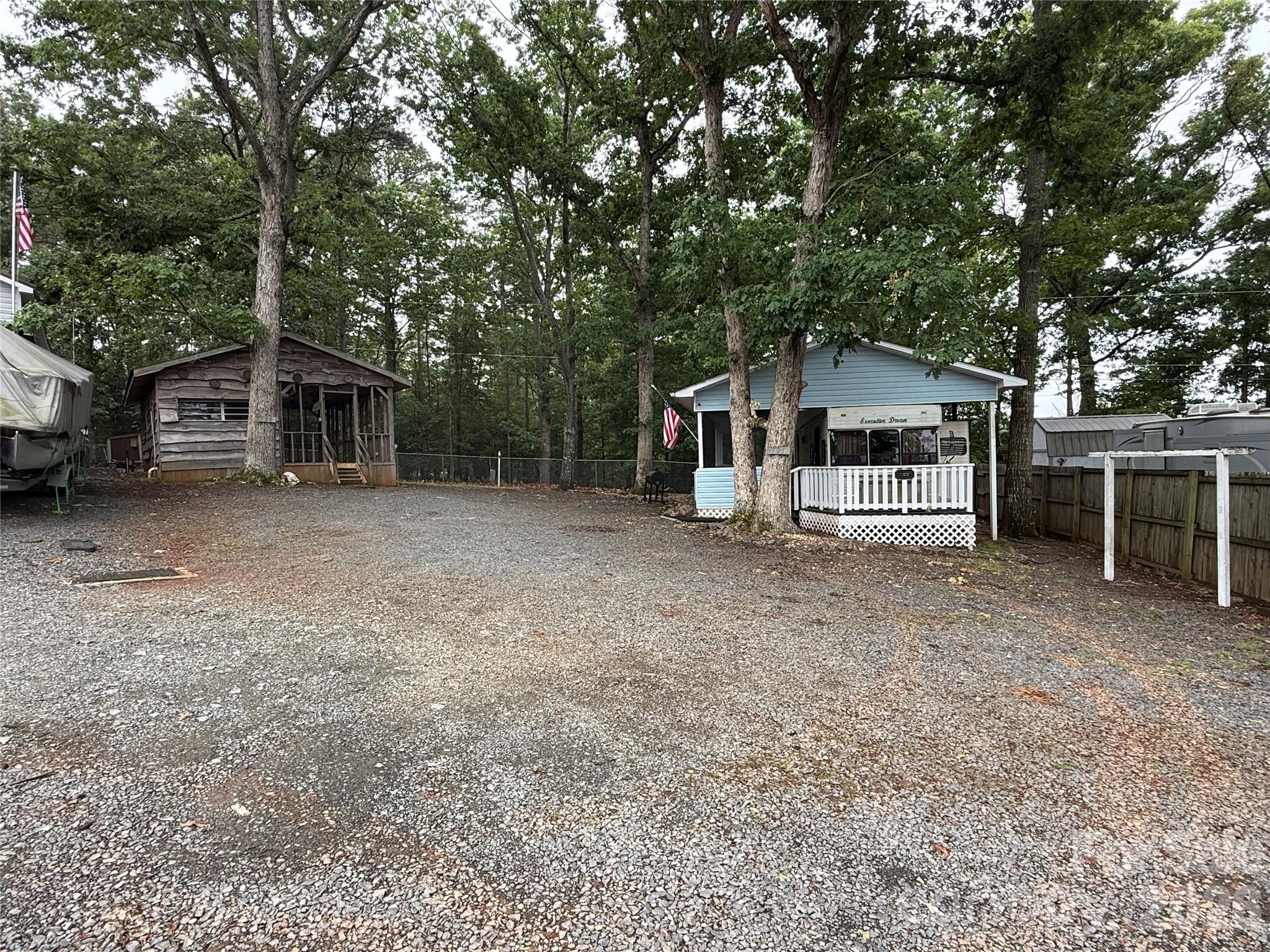 Rare Water View in Twin Harbor. 2 lots on a circle, 2 units, 1 is move in ready, the other needs work. 2 sewer taps, 2 power poles with 1 being active. 1 water tap. 109 Holly Cove Tr  (E101) host a 41' Executive Dream Camper with 2 slides and a 12' covered porch the length of the camper. 1 bedroom with queen, 1 bath with real potty. Front porch has view of the water as does the front end of the camper on the inside and a view from the bedroom windows.
107 Holly Cove Tr (E100) has a great view of the water from the porch. I love the log plank siding on this unit. The inside has been stripped and needs to be put back together or tear the whole thing down.  Water view from the front end of camper as well. 
Many options here. Tear it all down and bring in a park model. Update both and make the best of what is there.  There is plenty of parking for all your toys and cars. Having a water view is such a wonderful blessing. Calming and peaceful!!!!! 
"What would make this place Your Happy Place?" No titles to campers, bill of sale will be provided.
All buyers must be with a realtor to gain access to the community.
