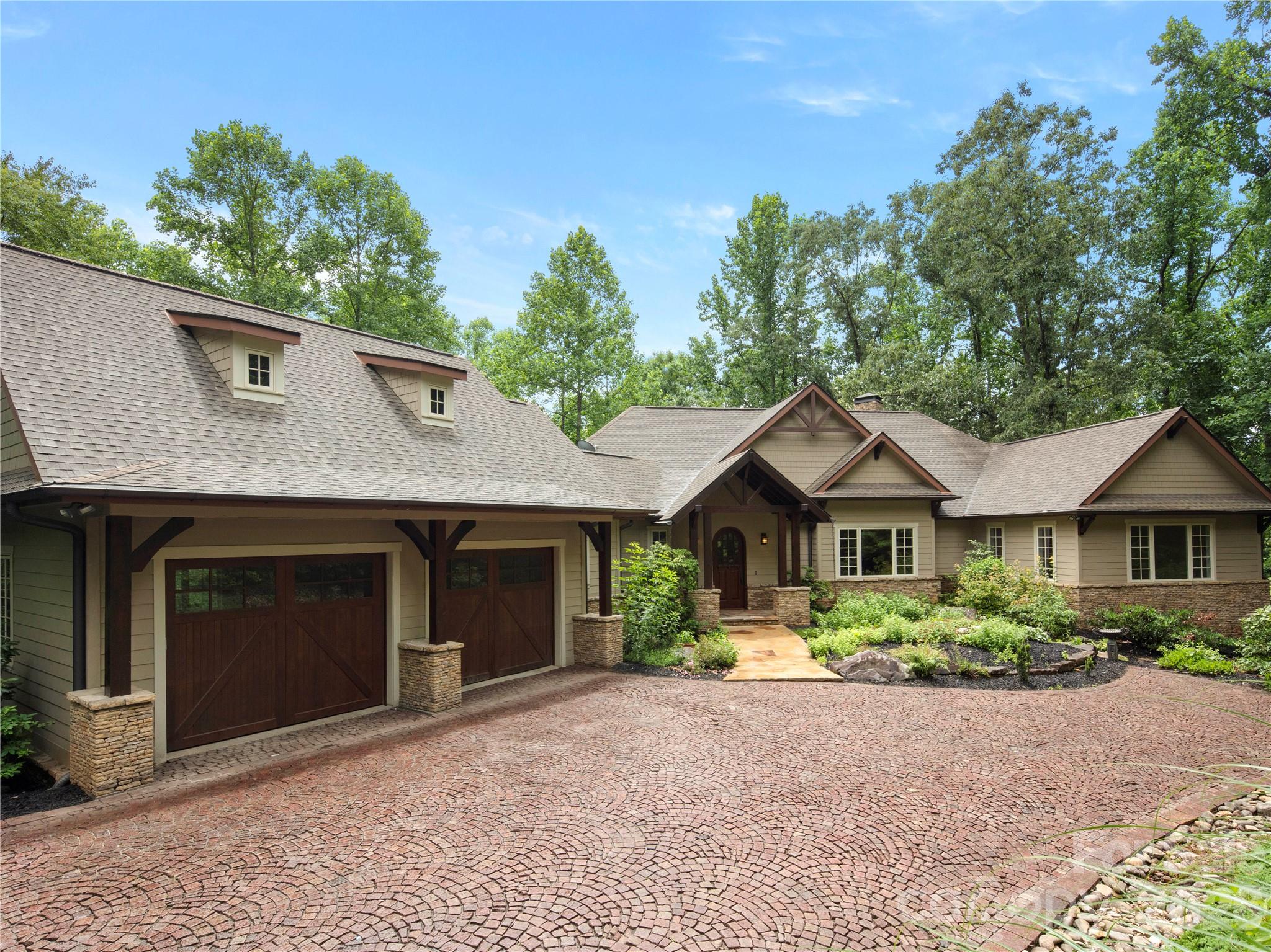 Step into a home where master craftsmanship meets artistic vision. Nestled within the premier gated enclave of The Cliffs at Walnut Cove in Arden, North Carolina, this stunning custom residence was thoughtfully designed and built by a fifth-generation carpenter whose legacy of precision, skill, and architectural integrity is reflected in every square inch. The journey begins outside on the grand, hand-laid cobblestone driveway inspired by ancient Roman roads, which wraps past lush perennial gardens to frame a stately mountain facade. Having undergone an extensive, top-to-bottom transformation in 2026, the interior showcases freshly updated premium hardwood flooring and meticulously redesigned, spa-like bathrooms that elevate the daily living experience. At the heart of the home, the sweeping great room is anchored by a striking stone wood-burning fireplace that pairs naturally with the bright, open spaces and high-altitude mountain privacy. This primary living area flows seamlessly into a chef’s dream kitchen, a space defined by rich chevron-patterned tile backsplashes, a professional appliance wall with double wall ovens, and premium light marble countertops that run all the way up to an elegant picture window overlooking the dense tree canopy. Serving as both a highly functional centerpiece and an extraordinary work of art is the custom South African blue-gray hardwood island, providing a generous setting for large-scale entertaining. Directly off the main level, expansive glass doors slide open to a private trex deck retreat nestled securely among the treetops for serene outdoor dining. Downstairs, the versatile terrace level functions as a private domain of its own, offering comfortable guest suites, flexible bonus space for recreation, a second dedicated laundry room, and a massive lower-level workshop. This unfinished workshop area also holds immense square footage potential to expand into an additional craft room, wine cellar, collector car storage, or extended media room. Beyond the property boundaries, a premier Cliffs membership unlocks an unparalleled, world-class mountain lifestyle centered around an 18,000-square-foot wellness center complete with indoor and outdoor pools, tennis courts, and a luxury full-service spa. Golf enthusiasts will revel in the community's crown jewel, a Jack Nicklaus Signature golf course that wanders beautifully through the valley landscape, complemented by an award-winning Tudor-style clubhouse and "The Tavern," a celebrated member social hub for fine dining and exclusive community events. Bordering the protected wilderness of the Pisgah National Forest and situated just minutes from both the iconic Blue Ridge Parkway and the vibrant cultural, dining, and artistic heartbeat of downtown Asheville, this timeless luxury estate offers the ultimate combination of secluded mountain luxury and elite resort convenience.