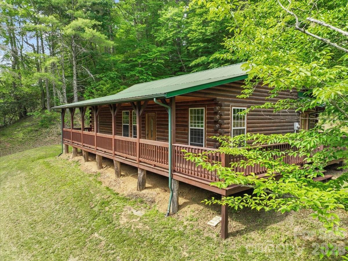 Welcome to this warm & inviting custom built log home nestled on a private 0.59-acre corner lot in the Green Mountain community of Yancey County. With its classic mountain charm this one-story cabin features an authentic log exterior, a sweeping, covered front porch perfect for relaxing & taking in the surrounding wooded landscape & seasonal mountain views. Inside, the home features rich tongue & groove pine across the walls & ceilings paired with a combination of hickory wood floors & tile throughout. The functional single-level floor plan offers an open & airy flow between the main living room with its cozy fireplace, kitchen with custom cabinetry & natural wood breakfast bar, adjacent dining room makes the space feel both spacious & intimate. The split bedroom layout offers a spacious primary bedroom along with another comfortable bedroom, home office or bonus room, two full bathrooms and a main level laundry area tucked conveniently off the hallway. The kitchen comes fully equipped w/ stainless steel appliances, custom cabinetry, and an open layout that transitions effortlessly to the multiple outdoor porches & deck areas. This property strikes the perfect balance between quiet mountain privacy & convenience. Situated just 10 minutes from the heart of downtown Burnsville, you can easily enjoy local shops, dining, and amenities. This home is a scenic 45 minute drive to the cities of Asheville, NC or Johnson City, TN.

--