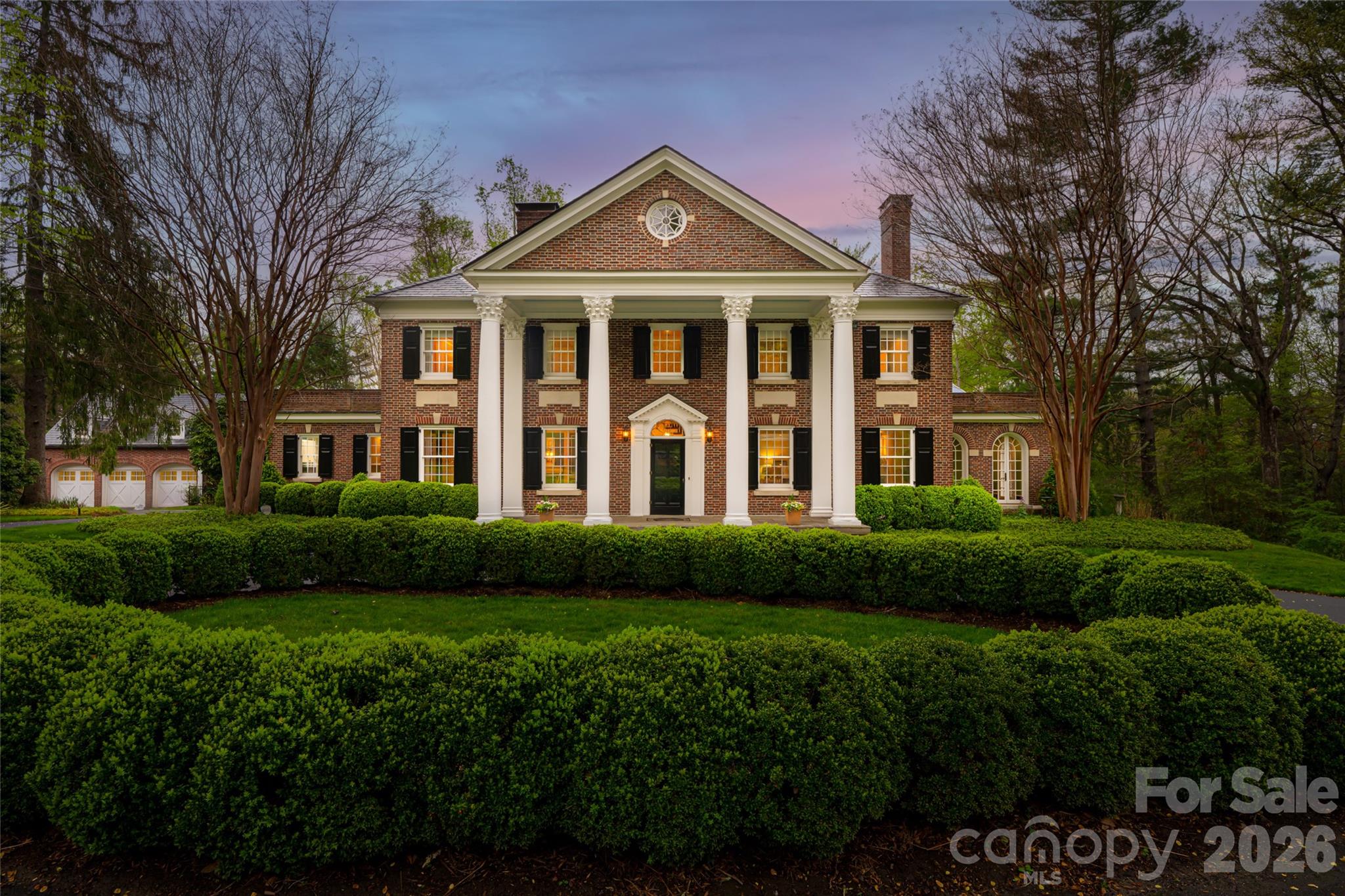 A masterwork of Georgian Revival elegance, this distinguished Biltmore Forest estate is a rare Asheville treasure of enduring beauty and provenance. Set on 3.32 acres near the Cedarcliff Gate of the Biltmore Estate, the residence was designed in 1927 by renowned Beaux-Arts architect William Lawrence Bottomley, one of his few Southern projects and a testament to his mastery of scale, proportion and grace. The classic brick façade opens to interiors rich with preserved historic detail, including quarter-sawn oak herringbone floors, leaded glass, original moldings and star-shaped light fixtures. Gracious formal rooms with wood-burning fireplaces flow with balance and symmetry. The restored living room opens through French doors to the gardens, while a cozy library with original bookcases offers an intimate retreat. A thoughtfully reimagined butler’s pantry preserves historic integrity while supporting modern living. The kitchen blends charm and function with granite countertops, double islands, upgraded appliances, and seamless flow to the family room and rear patio. Upstairs, the original layout has been transformed into generous suites, including a primary wing added in 1984, with additional guest quarters above the garage. Thoughtful updates such as slate roof, generator, HVAC zones and restored hardwoods ensure comfort without compromise. The grounds complete the offering with formal gardens, open lawns, a fish pond, woodland paths and refined landscape lighting.