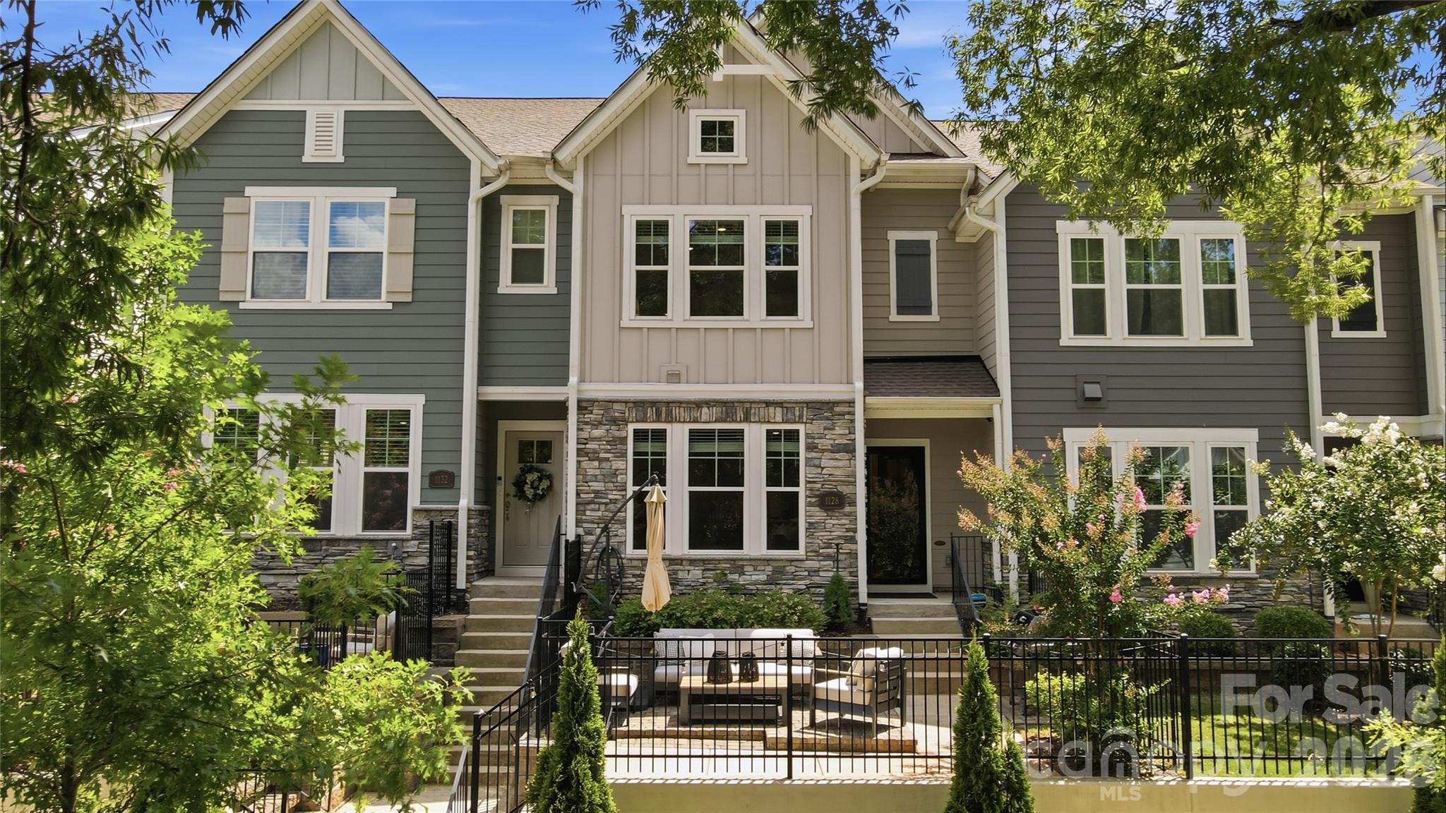 Welcome to 1128 Drummond Avenue, a light and bright townhome built in 2023 and ideally located within walking distance of NoDa and Plaza Midwood. Facing luxury homes and green space, the open front outlook provides beautiful views and a more spacious, residential setting.

The main level features an open-concept living, dining, and kitchen area designed for everyday living and entertaining. The gourmet kitchen offers quartz countertops, stainless steel appliances, a gas cooktop, wall oven, vent hood, tile backsplash, farmhouse sink, extensive cabinetry, an oversized island, and a walk-in pantry. Luxury vinyl plank flooring extends throughout the first and second levels, complemented by wood stair treads throughout.

Upstairs, the spacious primary suite includes a tray ceiling, walk-in closet, and spa-inspired bath with dual vanities and an oversized shower with bench seating. Two additional bedrooms, a full bath, laundry room, and versatile landing area complete the second floor. The carpeted third level provides a private fourth bedroom or flex space with a full bath, perfect for guests, a home office, media room, or second living area, plus walk-in attic storage.

Outside, enjoy a fenced, customized paver patio with a separate grilling pad. Additional upgrades include a reverse-osmosis water system and a finished | painted two-car garage. Conveniently located near the light rail, Greenway, Uptown, and popular neighborhood dining, shopping, and entertainment.