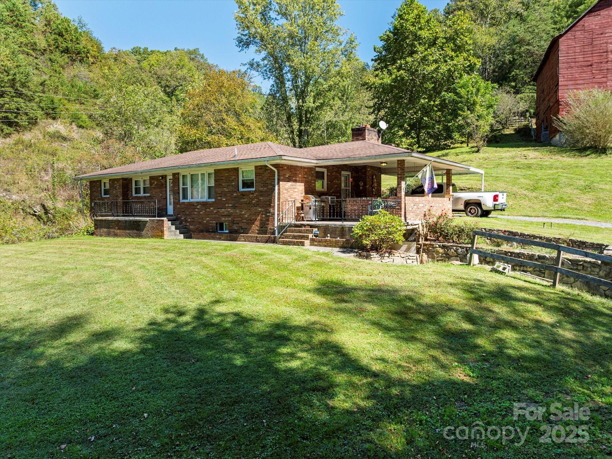 Welcome to a rare and extraordinary opportunity to own 137 acres of impeccably maintained land in the heart of nature along with a 3 bedroom, 1.5 bathroom brick ranch home. Whether you’re dreaming of a private estate, working farm, homestead, equestrian property, compound, or development project, this stunning property offers the versatility and natural beauty to bring your vision to life. This is your chance to own pristine mountain land with exceptional potential. Gently rolling pastures transition to steeper, wooded areas, offering a dynamic mix of open, usable space and forested terrain. The majority of the property is fenced (barbed-wire) and hot-wired, ideal for livestock or equestrian use. Currently used as a cattle ranch, the land is turn-key ready for agricultural pursuits or can easily be repurposed for recreation, conservation, or residential development. Multiple potential homesites dot the landscape, including locations at higher elevations with panoramic, long-range views of the Blue Ridge Mountains. Rough roads/trails are already in place leading to the top of the property, where the views are absolutely breathtaking—perfect for a future dream home or cabin. A spring on the land currently supplies water to the existing home, adding to the property's self-sufficient appeal. There’s also logging potential for those interested in timber resources. The 3-bedroom, 1.5-bath house offers flexibility. It can be renovated to your taste, used as temporary housing while you build, or kept as a guest home. A covered front porch invites you to relax and take in the surrounding beauty. A new septic system (2023), and newer roof (2018) and windows (2017), add to the value. Additional features include an idyllic, large barn that was once used for tobacco, and a tractor shed. The possibilities here are nearly limitless. Don’t miss your chance to explore all that this incredible property has to offer. Ten minutes to downtown Marshall and the grocery store, 30 minutes to downtown Asheville. The home, additional structures, and land are being sold as-is.