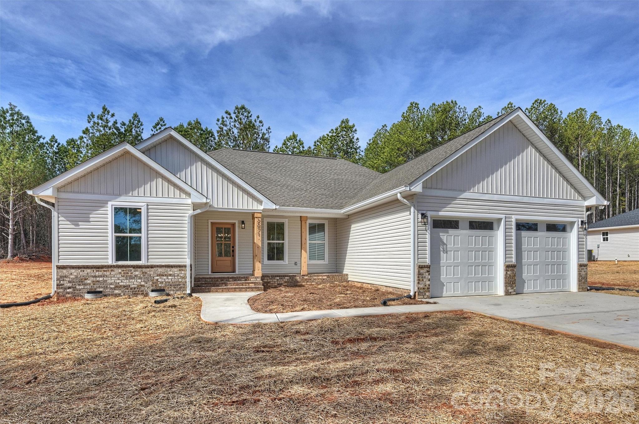 Recently completed and now available, welcome to North Pines—Lincolnton’s newest collection of thoughtfully crafted single-level homes by Brancer Homes. 2271 Lee Lawing Road blends elevated finishes, modern farmhouse charm, and the natural privacy of tree-lined homesites—all just 15 minutes from downtown Lincolnton and convenient to everyday shopping in Sherrills Ford and Denver.

The inviting exterior showcases classic brick accents and stained wood front-porch columns, delivering warm curb appeal with a clean farmhouse aesthetic. Inside, the builder’s Modern Farmhouse Designer Package combines crisp cabinetry finishes, curated lighting selections, stylish hardware, and quartz countertops throughout for a fresh yet timeless feel.

The open-concept kitchen features a spacious island with pendant lighting and flows seamlessly into the vaulted main living area, creating an airy, light-filled space ideal for both entertaining and daily living. The primary suite highlights a beautifully tiled shower wall and designer finishes that balance comfort with farmhouse-inspired character.

Additional features include added recessed lighting, a functional drop zone, and a well-appointed laundry room with upper cabinetry and quartz counters for enhanced storage and convenience. An extended two-car garage with exterior exit door, along with additional driveway parking, adds to the home’s everyday functionality.

Now that construction is complete, this home is part of a newly released collection in North Pines—offering a rare opportunity to own move-in ready new construction with elevated design and modern farmhouse appeal in one of Lincolnton’s fastest-growing areas.Additional features include added recessed lighting, a drop zone, and a laundry room with upper cabinets and quartz counter for extra storage and functionality. The home also includes an extended two-car garage with exterior exit door and additional driveway parking, making this layout as practical as it is stylish.

Set in a low-maintenance community with peaceful rural surroundings, this home pairs craftsmanship, modern design, and timeless farmhouse appeal—perfectly suited for life in Lincolnton.