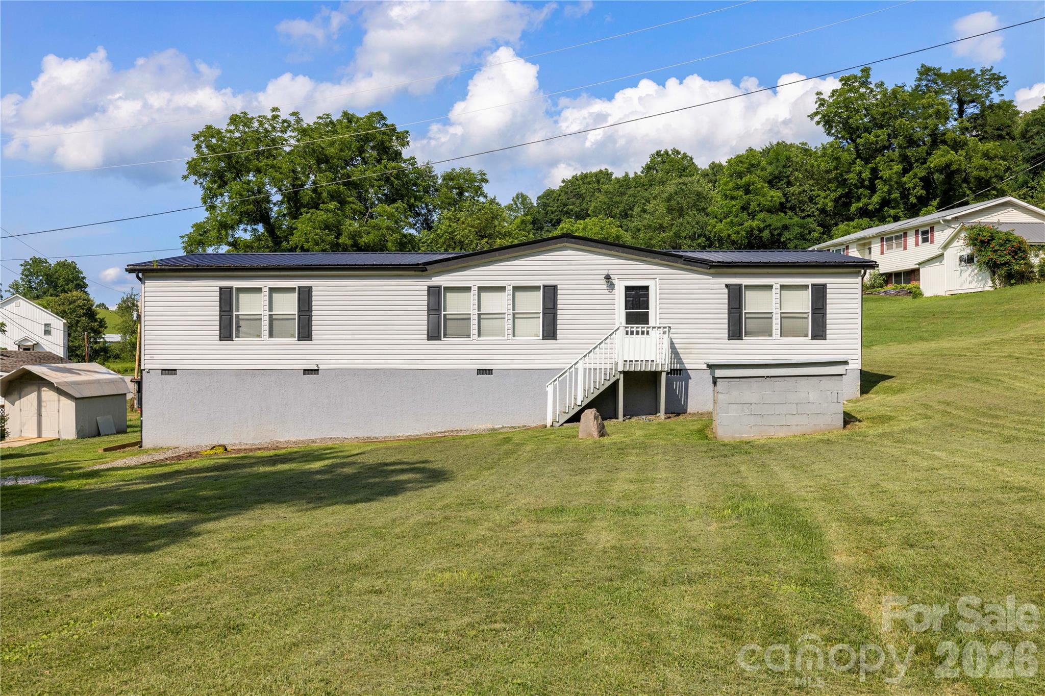 Tucked away in a peaceful mountain cove, this inviting home offers the perfect blend of privacy, comfort, and everyday convenience. Set on a spacious lot surrounded by mature trees, you'll love relaxing on the back deck, enjoying the quiet setting, or taking evening walks along the country roads. Outdoor enthusiasts will also appreciate nearby access to the Pigeon River for fishing, kayaking, camping and other adventures.

Inside, the open-concept floor plan creates an inviting space for gathering, with a generous living area that flows seamlessly into the dining room and kitchen. The primary suite is thoughtfully separated from the guest bedrooms and features a walk-in closet, double vanity, soaking tub, and walk-in shower. Two additional bedrooms, a full guest bath, and a dedicated laundry area complete the interior.

A durable metal roof offers lasting peace of mind, while the tall crawl space provides excellent storage. The gently sloping yard offers plenty of room to enjoy the outdoors, making this a wonderful opportunity to experience the quiet beauty of mountain living.