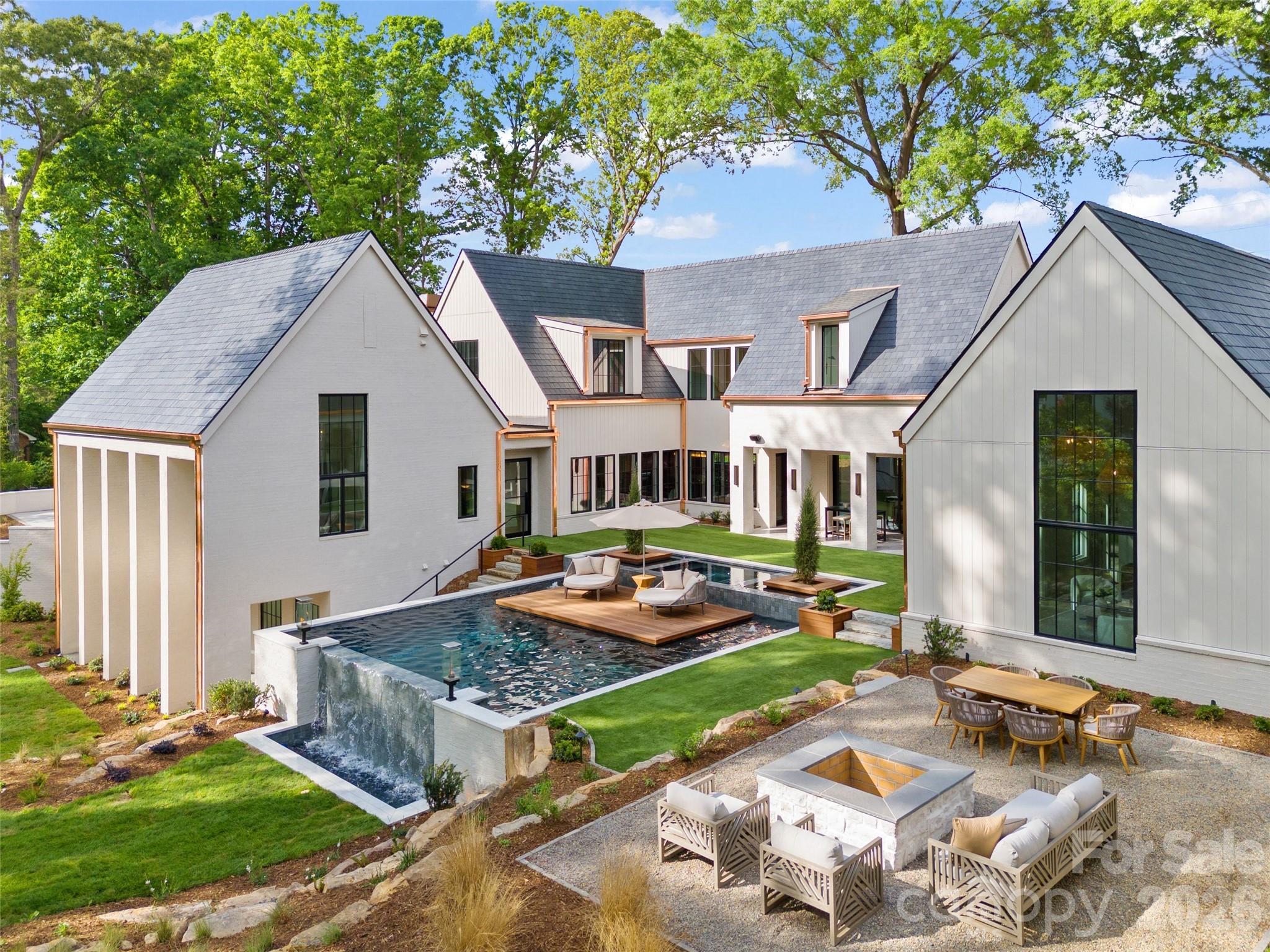 Welcome to another Grande Custom Builders masterpiece in the heart of Foxcroft, offering a seamless mix of elegance, sophistication, and modern livability. This architectural gem makes a commanding first impression with its slate roof, copper gutters, brick and stone exterior, and gas lanterns. This thoughtfully designed floor plan features 5+ bedrooms plus flexible living spaces, supported by six full and two half bathrooms.  GCB exclusive custom milled trim throughout, 
Kitchen has white oak inset cabinets, soapstone countertops, and a quartzite slab backsplash. 48" Wolf range, panel front dishwasher, and built-in Sub-Zero refrigerator and Freezer.  The scullery is conveniently located next to the garage/drop zone, has an additional dishwasher, prep sink, refrigerator, steam oven, Miele coffee machine, in cabinet microwave and plenty of storage. 
Living room is open to the kitchen and dining areas. A cozy ingle room centered around a gas fireplace, with solid wood pocket doors provides a quiet retreat. The design works with Carolinas' climate with an indoor-outdoor den featuring two sets of twelve-foot glass sliders that retract flush into the walls.
The owner’s suite has heated bathroom floors, a large dual-spray shower, and a stand-alone concrete bathtub. The custom closets includes integrated cabinet lighting and dedicated space for a stackable washer and dryer. 
The wellness wing is a standout feature of this home overlooking the pool built by Tidal Custom Pools, formerly GCB Pools.  This space is complete with hydronic heated floors throughout and has a living room, guest suite, and a kitchenette. The full bath offers a steam bath, cold plunge and sauna.
Upper-level includes a large laundry room, versatile bonus room, private office, three secondary bedrooms, and 3 full baths. The expansive walk-out basement has a dedicated game area wired for a projector or golf simulator, alongside a light-filled gym with wall of windows overlooking the yard.  There is an attached two-stall garage featuring a finished room and half bath above, complemented by an additional one-stall detached garage. Outside, you'll find a GCB original custom-designed pool, fire pit, outdoor kitchen, and extensive landscaping to optimize privacy.