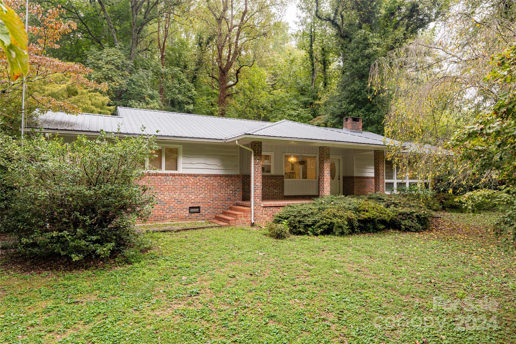 Escape to your own private retreat, just minutes from charming downtown Tryon. This 3-bedroom, 2-bath home, set on a serene private road, offers the perfect balance of tranquility and convenience. The kitchen shines with granite countertops, ample cabinetry, and tile flooring, while the versatile dining room, complete with a closeted laundry, can be transformed into a family room, game room, or even a billiard room. The light-filled living room features hardwood floors, a beamed ceiling, and large windows that bathe the space in natural light. Three spacious bedrooms with hardwood floors and deep closets offer both style and functionality. Outside, the detached L-shaped double garage includes a finished 20x28 workshop, ideal for an office, craft space, or home gym. The large grassy area, bordered by a peaceful stream, is perfect for outdoor enjoyment. Discover this distinctive, private haven—schedule your tour today!