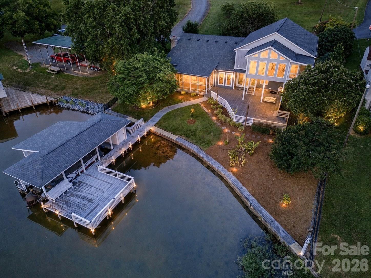 Welcome to lake life at its finest on beautiful Lake Tillery! This fully furnished waterfront retreat with sunset view is tucked away in a wide, quiet cove and offers the perfect blend of comfort, space, and outdoor living.

The boathouse is designed for making memories, featuring a boat slip, spacious sundeck and a large covered lounging area ideal for relaxing after a day on the water. A short, gentle walk leads you from the home to the shoreline, making lake access effortless, where the fish are abundant!

Inside, the impressive great room is filled with natural light and showcases soaring vaulted ceilings and a stunning rock fireplace that creates a warm, inviting atmosphere. The kitchen is equally impressive with granite countertops, a generously sized island, and plenty of lovely cabinetry.

The main floor offers two comfortable bedrooms and a full bath, while upstairs features an extraordinary primary suite unlike anything you’ve seen before. This oversized retreat includes a spa-like en suite bath with dual vanities, soaking tub, separate shower, two walk-in closets with laundry connections, plus a private sunroom and screened porch overlooking the lake. An additional bonus room upstairs provides the perfect space for a home office or flex room.

The garage offers room for one vehicle plus extra space for a workshop, golf cart parking, or lake toys. A separate living quarters with private entrance from the garage includes its own kitchen, laundry, and full bath — ideal for guests, extended family, or rental potential.

Outdoor living shines throughout the property with mature landscaping, productive fig tree and blueberry bushes, a screened porch, expansive deck, fenced backyard and a cozy fire pit area perfect for watching the sunset.

Whether you’re searching for a full-time residence, vacation getaway, or income-producing lake property, this exceptional Lake Tillery home delivers the ultimate waterfront lifestyle.

(Second Living Quarters, Sunroom and Upper Porch were added by former owners without obtaining permits)