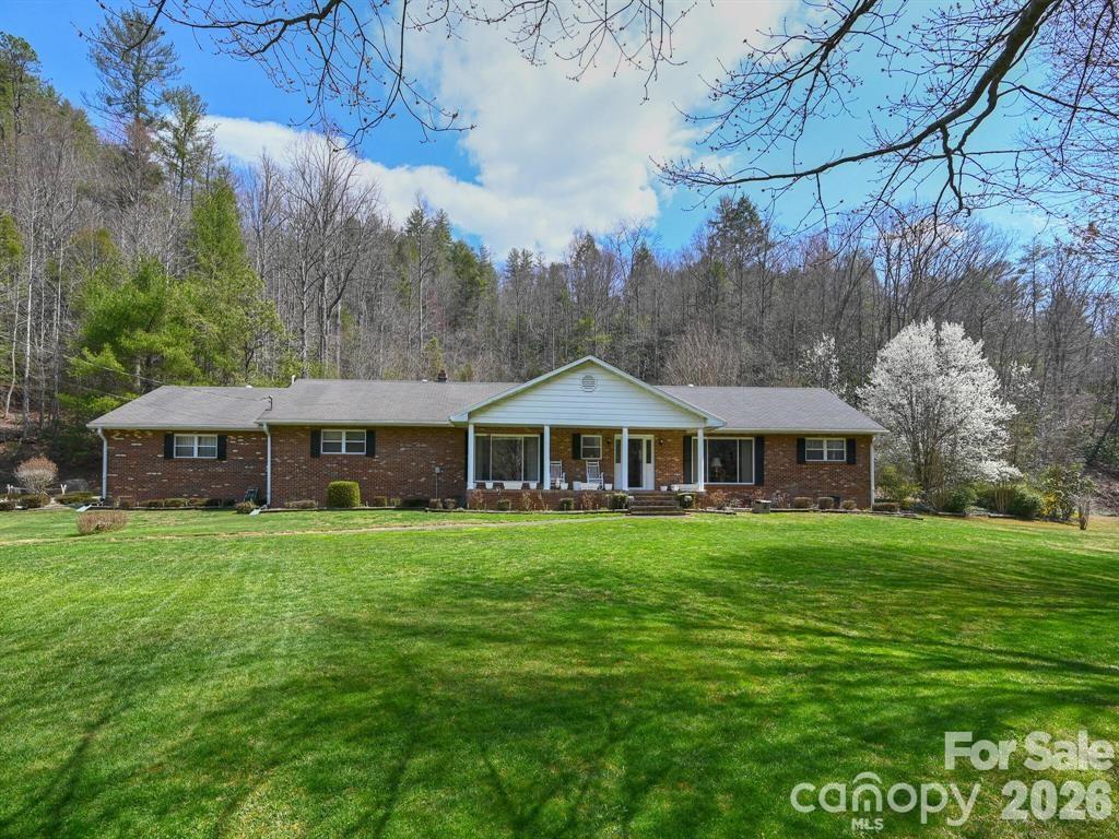 Welcome to 7530 NC 208 Hwy., a true gem nestled in the scenic beauty of Madison County! This 4 bedroom brick home is overlooking the prestigious Little Laurel River. Perfectly positioned on a large flat well-manicured yard of a sprawling 36+ acres that borders the US Forest. The backyard features an oversized canning house, covered porch creating a private oasis where you can enjoy your morning coffee w/ family, friends & pets. Enjoy a short drive to the Allen Gap trail head of the Appalachian Trail for many miles of hiking. Inside of the home you will find a split bedroom plan, spacious kitchen that is open to the dining room, family & living room. The attic offers a lot of storage possibilities! This property was once a family ran trout farm! This property offers so many possibilities to update and make it your own. There is a portion of the house that has hardwood flooring underneath the carpet per the owner. Less than 20 mins to Hot Springs, Approx. 30 minutes or less to Marshall and Downtown Greeneville, TN.
