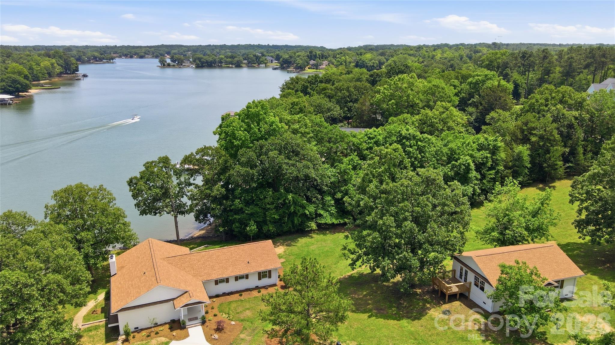 Extraordinary waterfront retreat on 1.47 acres with gentle slope and breathtaking views of Lake Wylie. This extensively renovated home offers the perfect blend of luxury, comfort, and outdoor living.  No detail was overlooked during the recent restoration to include solid White Oak hardwood floors, new drywall, paint, insulation, electrical, plumbing, Pella Clad Wood windows, doors,  new roof, kitchen cabinets, appliances, counters, bathrooms, plumbing fixtures, light fixtures, new siding, paver patios, landscaping, and extensive trim work.  Designed for entertaining, the lake-facing great room features a cozy fireplace and flows seamlessly into the formal dining room and gourmet kitchen, complete with stainless steel appliances, 36" Viking gas range, Microwave Drawer, Bosch Dishwasher, center island, abundant counter space, and casual breakfast area. The luxurious primary suite is a private retreat with a custom walk-in closet, private balcony overlooking the water, and spa-inspired bath. Two additional bedrooms, laundry room,  and a full bath complete the main level. The walk-out lower level offers a spacious recreation room with fireplace, full bath, and a huge storage room, providing flexible space for guests, hobbies, or recreation. Step outside to your own outdoor oasis featuring a level lakeside yard, two spacious paver patios, private dock with lift, and endless opportunities to enjoy lake living. An 882-square-foot detached cottage provides excellent space for a future home office, studio apartment, or guest accommodations. There is even a third detached building near the lake that is perfect for storage, workshop, or hobby space.  With NO HOA, South Carolina taxes, and a great location close to Rock Hill shopping and dining  this exceptional property is a rare opportunity to enjoy the best of Lake Wylie living.