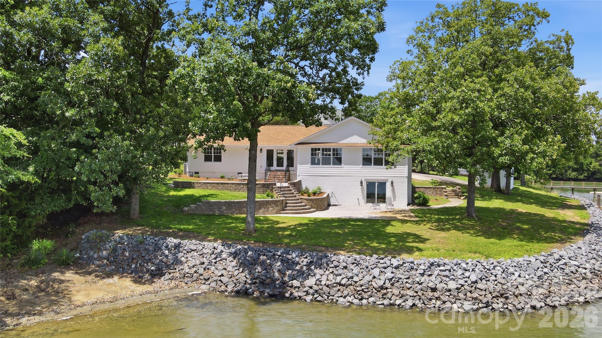 Extraordinary waterfront retreat on 1.47 acres with gentle slope and breathtaking views of Lake Wylie. This extensively renovated home offers the perfect blend of luxury, comfort, and outdoor living.  No detail was overlooked during the recent restoration to include solid White Oak hardwood floors, new drywall, paint, insulation, electrical, plumbing, Pella Clad Wood windows, doors,  new roof, kitchen cabinets, appliances, counters, bathrooms, plumbing fixtures, light fixtures, new siding, paver patios, landscaping, and extensive trim work.  Designed for entertaining, the lake-facing great room features a cozy fireplace and flows seamlessly into the formal dining room and gourmet kitchen, complete with stainless steel appliances, 36" Viking gas range, Microwave Drawer, Bosch Dishwasher, center island, abundant counter space, and casual breakfast area. The luxurious primary suite is a private retreat with a custom walk-in closet, private balcony overlooking the water, and spa-inspired bath. Two additional bedrooms, laundry room,  and a full bath complete the main level. The walk-out lower level offers a spacious recreation room with fireplace, full bath, and a huge storage room, providing flexible space for guests, hobbies, or recreation. Step outside to your own outdoor oasis featuring a level lakeside yard, two spacious paver patios, private dock with lift, and endless opportunities to enjoy lake living. An 882-square-foot detached cottage provides excellent space for a future home office, studio apartment, or guest accommodations. There is even a third detached building near the lake that is perfect for storage, workshop, or hobby space.  With NO HOA, South Carolina taxes, and a great location close to Rock Hill shopping and dining  this exceptional property is a rare opportunity to enjoy the best of Lake Wylie living.