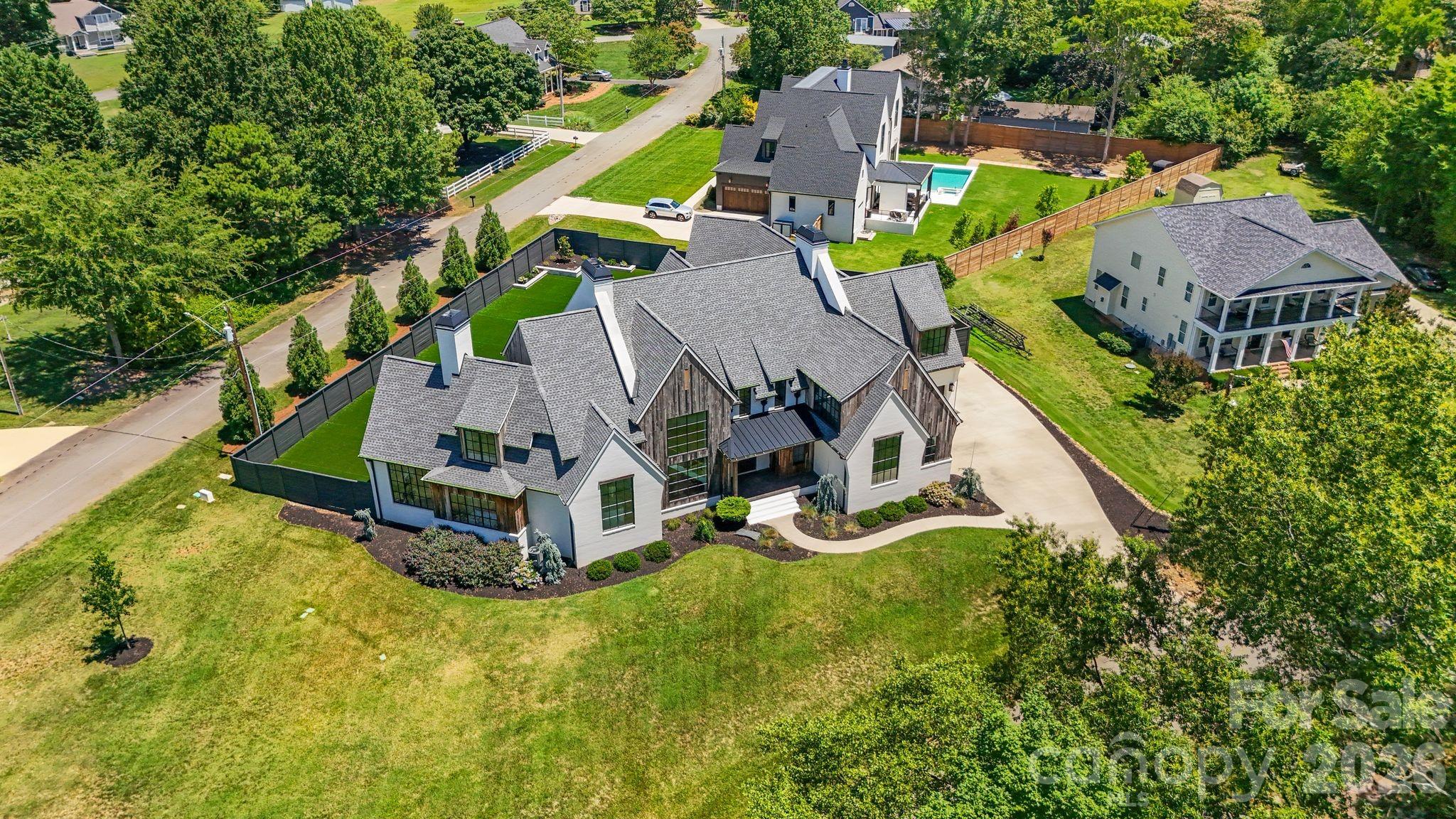 Modern luxury meets effortless lakeside living in this exceptional Lake Norman retreat. Framed by breathtaking water views and a private outdoor oasis, this architectural masterpiece blends contemporary sophistication with timeless craftsmanship.
The exterior showcases reclaimed barn wood sourced from historic barns across North Carolina, creating a warm organic contrast to the home's sleek modern design. A striking steel front door opens to an expansive open-concept interior where French white oak flooring flows seamlessly throughout.
Every detail has been thoughtfully curated—from the designer finishes to the impeccable functionality. The main level features an elegant owner's suite with a spa-inspired ensuite, a private fitness studio complete with traditional and infrared saunas, a dedicated office/flex space, full bath, and an entertaining bonus room highlighted by custom swinging barstools. Upstairs, five additional bedrooms and a second bonus space offer refined comfort with a sophisticated, functional layout designed for modern living.
At the heart of the home, the chef's kitchen is a true showpiece featuring premium Thermador appliances, an oversized quartzite island, and a fully equipped scullery designed for effortless entertaining. Dual laundry rooms add everyday convenience without compromising luxury.
Step outside and discover a resort-style outdoor living experience. The enclosed sunroom with fireplace overlooks the beautifully fenced backyard and an impressive oversized saltwater pool with integrated hot tub, creating the perfect setting for relaxation and entertaining. Whether enjoying a peaceful morning swim, unwinding in the spa at sunset, or hosting guests poolside, this private retreat captures the essence of luxury living. The outdoor space also includes a custom separate fenced dog run with artificial turf, ensuring every member of the household is thoughtfully accommodated.
Two tankless water heaters and countless additional upgrades further elevate this remarkable residence. This home is a statement of contemporary elegance, exceptional craftsmanship, and elevated luxury living.