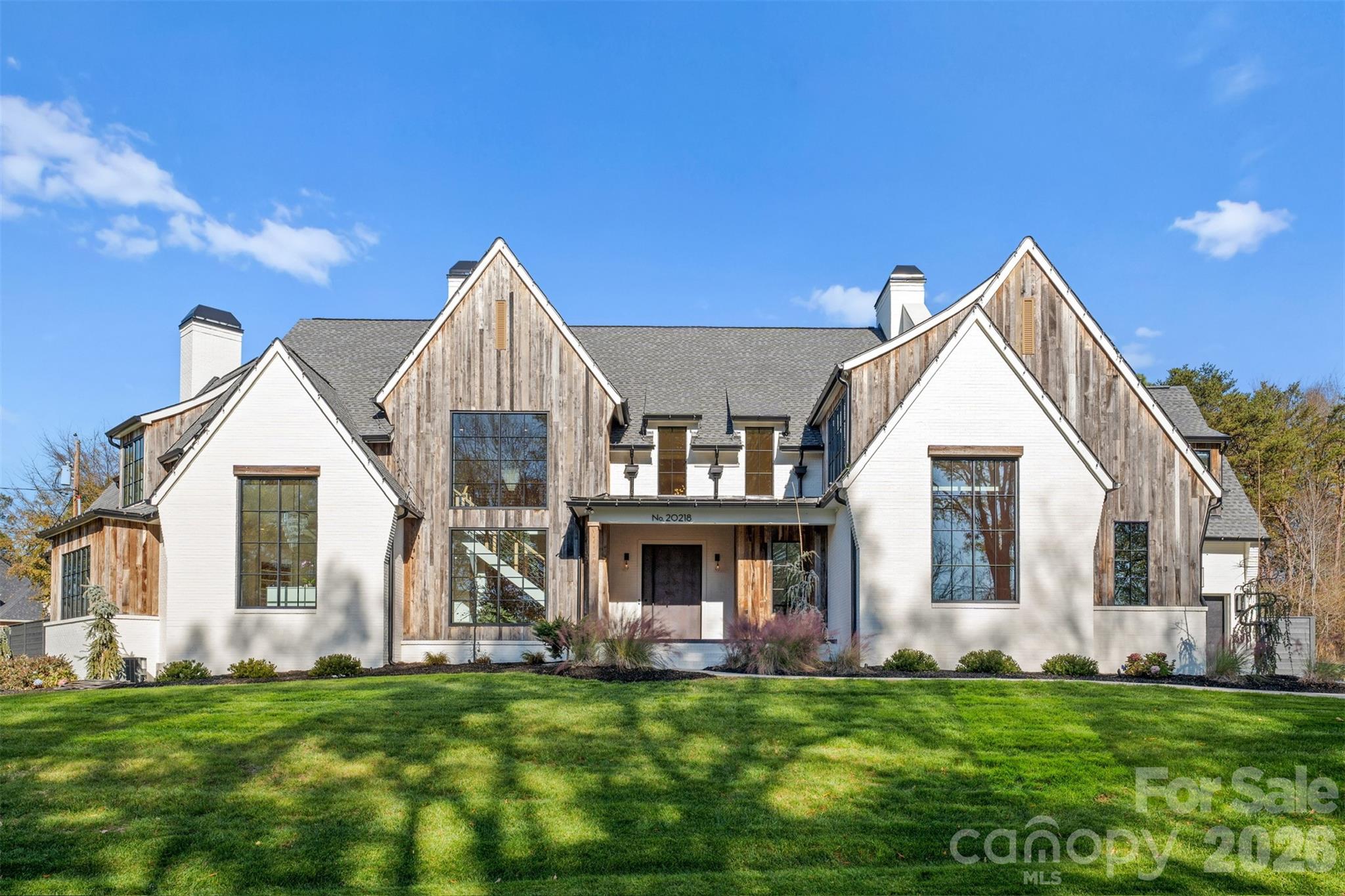 Modern luxury meets effortless lakeside living in this exceptional Lake Norman retreat. Framed by breathtaking water views and a private outdoor oasis, this architectural masterpiece blends contemporary sophistication with timeless craftsmanship.The exterior showcases reclaimed barn wood sourced from historic barns across North Carolina, creating a warm organic contrast to the home’s sleek modern design. A striking steel front door opens to an expansive open-concept interior where French white oak flooring flows seamlessly throughout.
Every detail has been thoughtfully curated — from the designer finishes to the impeccable functionality. The main level features an elegant owner’s suite with a spa-inspired ensuite, a private fitness studio complete with traditional and infrared saunas, a dedicated office/flex space, full bath, and an entertaining bonus room highlighted by custom swinging barstools. Upstairs, five additional bedrooms and a second bonus space offer refined comfort with a sophisticated, functional layout designed for modern living. At the heart of the home, the chef’s kitchen is a true showpiece featuring premium Thermadore appliances, an oversized quartzite island, and a fully equipped scullery designed for effortless entertaining. Dual laundry rooms add everyday convenience without compromising luxury. Step outside to an enclosed sunroom/porch with a fireplace overlooking the beautifully fenced backyard, and custom oversized pool complete with a separate fenced dog run featuring artificial turf. Two tankless water heaters and countless additional upgrades further elevate this remarkable residence. This home is a statement of contemporary elegance, exceptional craftsmanship, and elevated luxury living.