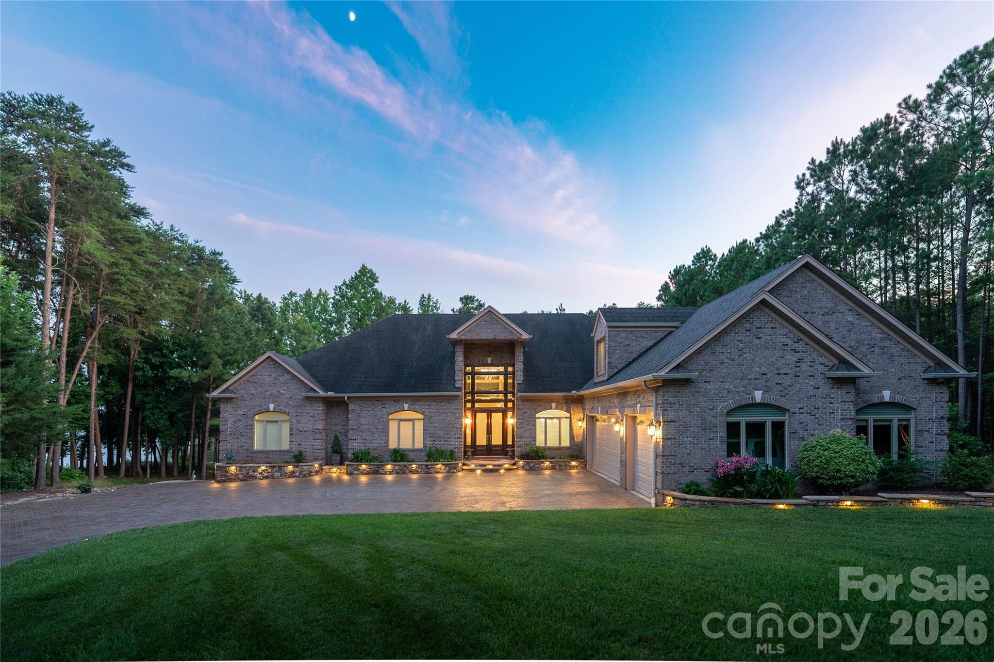 This spectacular 10,144 square foot waterfront home has a private boat dock and indoor pool/spa. If you're looking for a private retreat in an exclusive community, this is the home for you.
Nestled on the shores of Badin Lake with over 200 feet of private shoreline, this premier waterfront retreat offers captivating lake views and effortless lake living. Just steps from the renowned Old North State Club, ranked among Golf Digest’s top courses, the property features a lighted dock with a boat lift and three Jet Ski lifts. An exceptional indoor pool retreat awaits with travertine floors, cedar storage, dry sauna, stone fireplace, and hot tub, designed for year-round enjoyment in a peaceful setting. Four on-suite bedrooms, with a huge primary suite. Two full kitchens(main level and basement) with a dumbwaiter for effortless connection. Updated appliances. New dehumidifer in the pool/spa. Four A/C units were replaced in 2020. Other standout features include, Sonos Sound System and HikVision security system to name a few. Please see the attached features list for more details. The home is located in the gated community of Heron Bay.