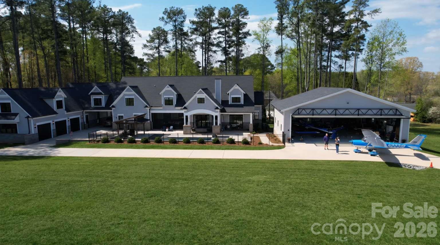PRICED BELOW MARKET VALUE! Farmhouse style home built in 2022 at the Lake Norman Airpark blending luxury, comfort, and aviation lifestyle. The open-concept interior centers on a chef’s kitchen with Viking range, 11' island, and 9” hickory floors. The main-level owner’s suite offers his and her bathrooms and separate walk-in closets. While upstairs movie room and office provide flexible living and workspace. Outdoor living includes a 34’x16’ saltwater pool, spa, pavilion grilling area, and 3-car garage with covered drive-through. There is an unfinished apartment with private entrance and a 1,138 sq ft upper level that has been furred out and ready for drywall. This property faces the 3,000’ paved airport runway with direct taxiway access. The 50’x40’ hangar includes a 44’x11’ Higher Power hydraulic door, mezzanine, radiant overhead heat, and attached 36’x24’ epoxy-floored workshop. Airpark amenities include fuel, tie down, hangars, and flight school. Runway repaving set for May 2026.