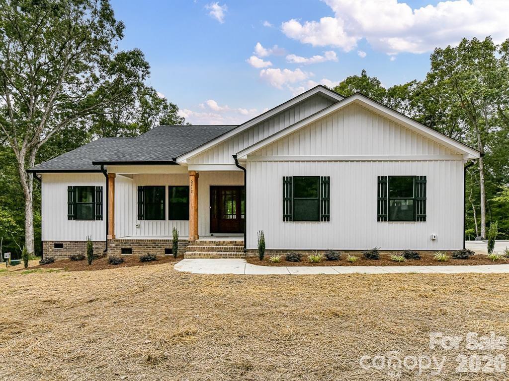 To Be Built. Discover your private oasis in this new construction modern farmhouse! Nestled on 2.367 wooded acres, this charming ranch home features high-quality craftsmanship. Enjoy the durability of maintenance-free vertical board and batten vinyl siding, complemented by sleek black windows and gutters. At the heart of the home, a spacious open living area flows seamlessly to the back covered and open deck, perfect for entertaining or relaxing. The large kitchen boasts custom soft-close cabinets, a sizable center island with ample bar seating, and high-end stainless steel appliances. The expansive dining area is ideal for a large farmhouse table. The generous primary bedroom includes a walk-in closet and a luxurious ensuite with dual vanity sinks, granite countertops, and a tiled walk-in shower with a glass door. Two additional bedrooms share a well-appointed bathroom. Enjoy the serene front porch, perfect for a swing or rocking chairs, and take advantage of the attached two-car garage. No HOA. TO BE BUILT. Pictures are from previous build by the builder and same plan.  Subject to change finishings.