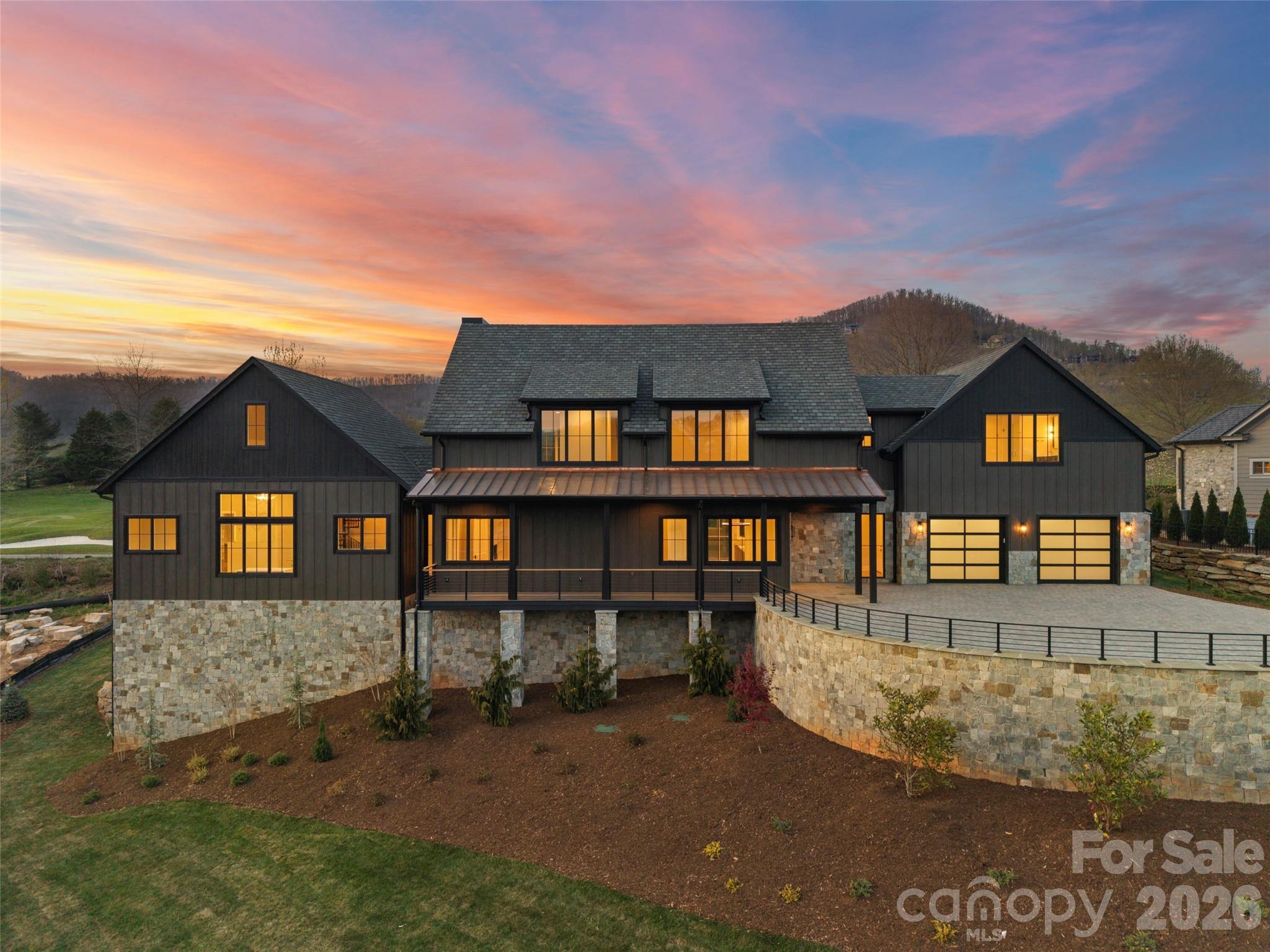 Perched within the prestigious gates of The Cliffs at Walnut Cove, this transitional mountain masterpiece in Arden, NC, offers an unparalleled lifestyle defined by luxury and natural beauty. The residence greets guests with a striking stone-clad exterior and a grand foyer featuring soaring ceilings and elegant glass-paneled barn doors that open onto the Jack Nicklaus Signature golf course. At the heart of the home, the expansive great room showcases a contemporary linear fireplace set against a floor-to-ceiling feature wall, flanked by custom backlit shelving and framed by a massive sliding glass wall that invites the outdoors in. The gourmet kitchen is a chef’s dream, anchored by a large island and professional-grade appliances, while a sophisticated wine room with custom vertical racking serves as a stunning focal point for entertainers.

The main level is thoughtfully designed for effortless living, highlighted by a primary suite that serves as a true sanctuary, complete with dual walk-in closets and a spa-inspired bathroom featuring a freestanding soaking tub and an oversized walk-in shower enveloped in floor-to-ceiling marble. Practicality meets luxury with a spacious mudroom, a large laundry center, and an elevator providing easy access to the upper level. Upstairs, the home continues to impress with a versatile bonus room and three additional bedroom suites, each offering private baths and walk-in closets to ensure comfort for family and guests alike.

Outdoor living is elevated to an art form, featuring a sprawling sun deck and a screened porch that overlook the lush fairways of the Jack Nicklaus Signature golf course. Along with a grilling station and outdoor refrigerator - the manicured stone patio offers the perfect setting for cool mountain evenings under the stars. With a Cliffs membership, residents gain access to world-class amenities including a state-of-the-art wellness center, indoor and outdoor pools, and fine dining at The Tavern. Bordering the Pisgah National Forest and situated just minutes from the Blue Ridge Parkway and the vibrant culture of Asheville, this property represents a rare opportunity to enjoy high-altitude privacy without compromising on convenient access to premier recreation and amenities.