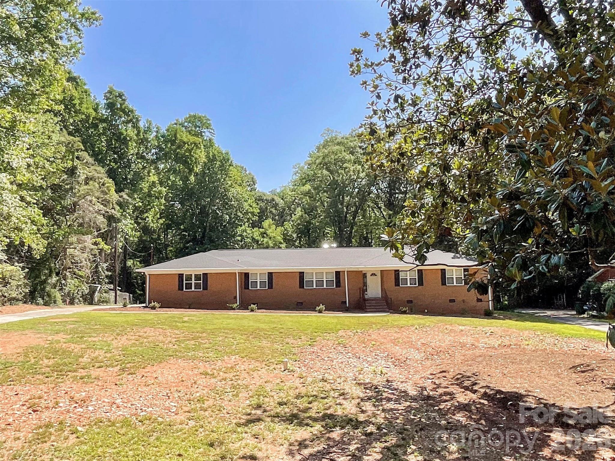 This charming 1963 brick-and-wood ranch home offers a rare opportunity on 2.24 wooded acres in east Charlotte. With 1,684 sq ft, 3 bedrooms, and 2 full baths, this single-story home features a functional layout including a living room with fireplace, separate dining room, kitchen, family room, and spacious primary suite. Enjoy abundant natural light, wood and tile flooring, and a peaceful, tree-filled setting with plenty of privacy. The property includes a 2-car attached garage plus additional detached carport parking plus an outbuilding for storage or hobbies. The large, wooded lot is perfect for outdoor enjoyment, gardening, or creating your own private retreat while still being conveniently located in Mecklenburg County with easy access to shopping, dining, parks, and major roadways.