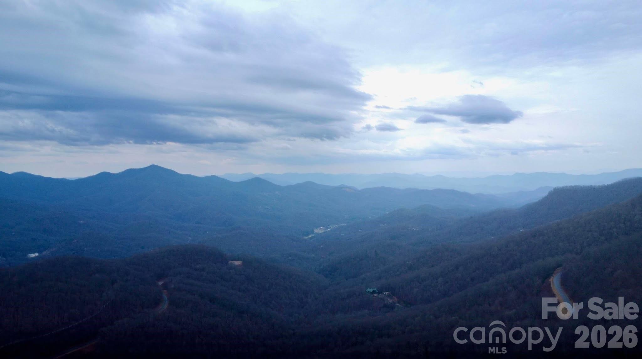 A truly spectacular parcel is now available in Hi-Mtn on top of Balsam. Situated conveniently between Waynesville and Sylva giving one the option of both towns for shopping, dining, recreation and healthcare. Imagine driving to your new home situated at 4590' elevation and literally looking down upon the Blue Ridge Parkway as you make that drive. The Mountains to Sea Trail runs adjacent to the Parkway in this section and affords you to walk out your door and access this trail for daily fitness hikes. Very gentle topography with an exceptionally easy building site. Literally adjacent to and overlooking the iconic Blue Ridge Parkway. Recently expired 4 bedroom septic permit and expired well permit. Recorded survey in 2021. Minimum size home is 1250 sq ft and does come with an $800 per year HOA due in order to maintain the road system and gate. Do not miss out on this exceptional opportunity with this high elevation, west facing building lot overlooking the Blue Ridge Parkway.