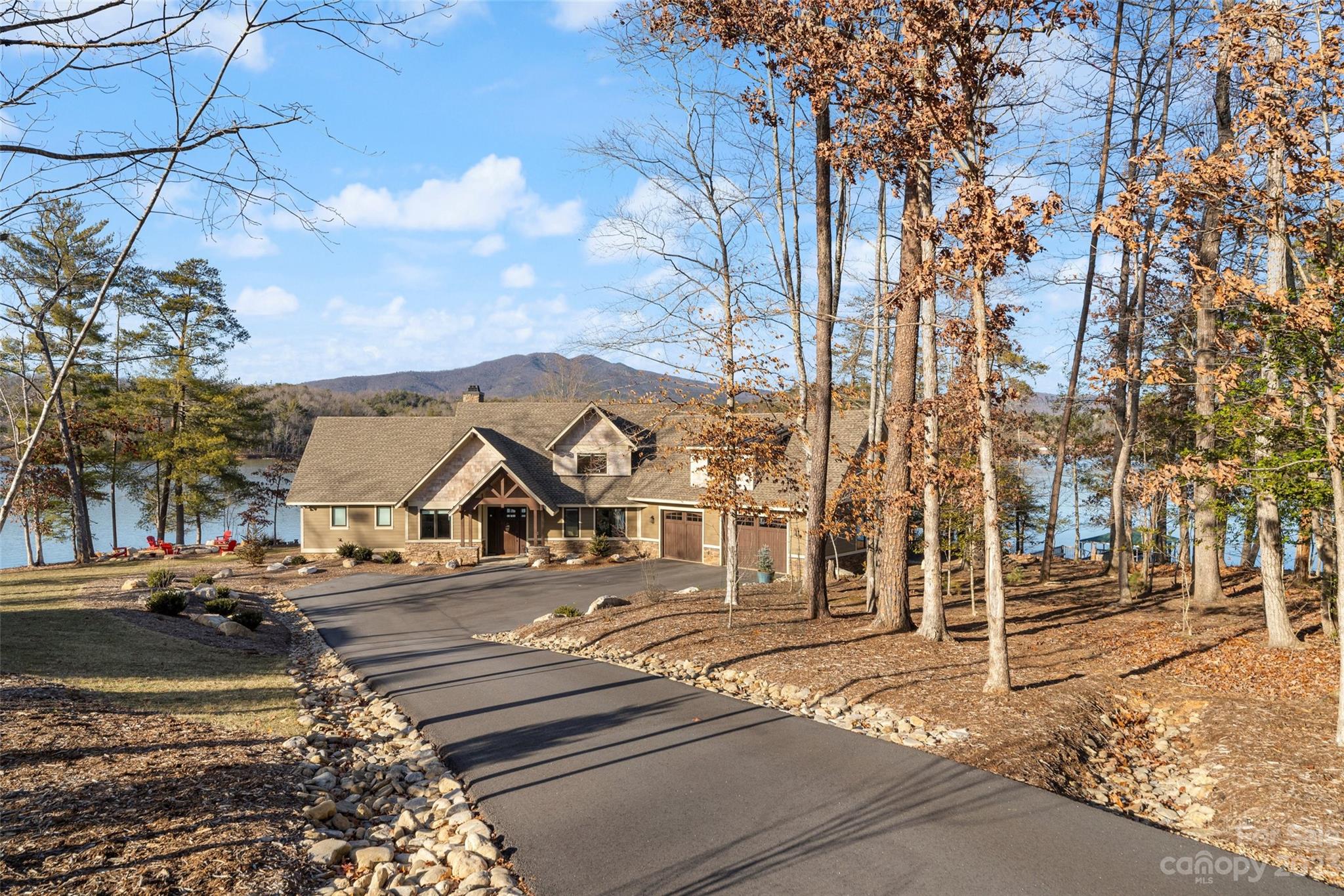 Here's a rare opportunity for a beautiful custom built home on 1.17 acre level peninsula lot with over 300ft of lakefront. Enjoy the amazing mountain views of Shortoff and Dobson's Knob. Panoramic views of the lake from nearly every room. Home features cathedral ceilings w/ wood beams, built-in bookcases and wood burning FP w/ gas starter. Kitchen features GE Kitchen Hub, quartz countertops, gas stove top, wine cooler and lots of cabinetry.  7" wide engineered French oak floors throughout.  Main floor master bedroom features cathedral ceilings, walkout access to your hot tub and a large walk-in closet. Master bathroom does not disappoint. Relaxing soaking tub with more amazing views and elegant shower with pebble floor. Upper level features 3 bedrooms and 2 full baths. Could be a second master suite. Oversized garage with epoxy floor w/ chip sealant and utility sink.  Lots of storage. Outdoor fire pit, gazebo, 20.5ft Chaparral bow rider, hydro hoist lift and Wahoo alum floating dock.